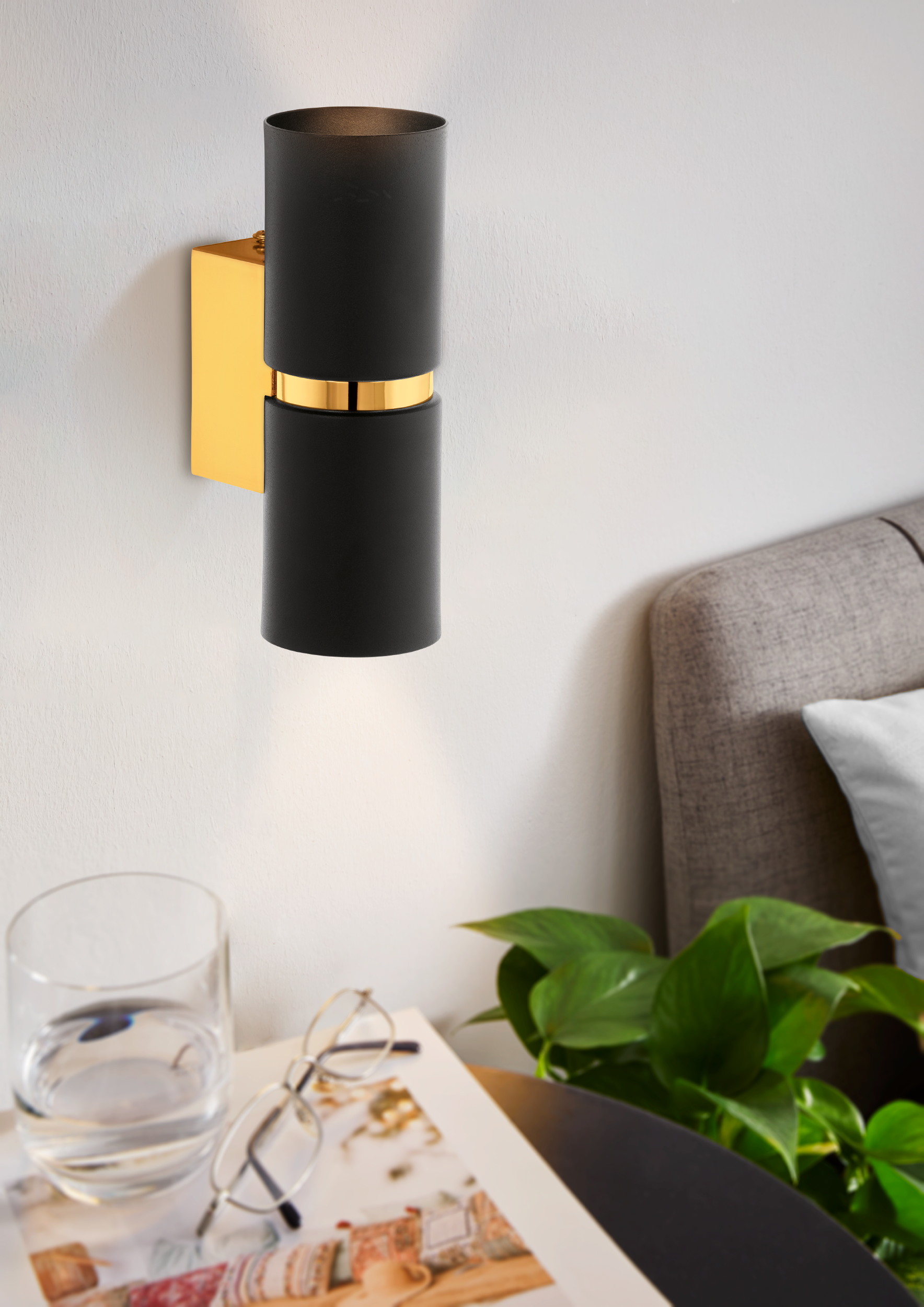 Schwarze und goldene Wandlampe, Glas Wasser, Brille, Zeitschrift, Pflanze, Bett im Hintergrund.