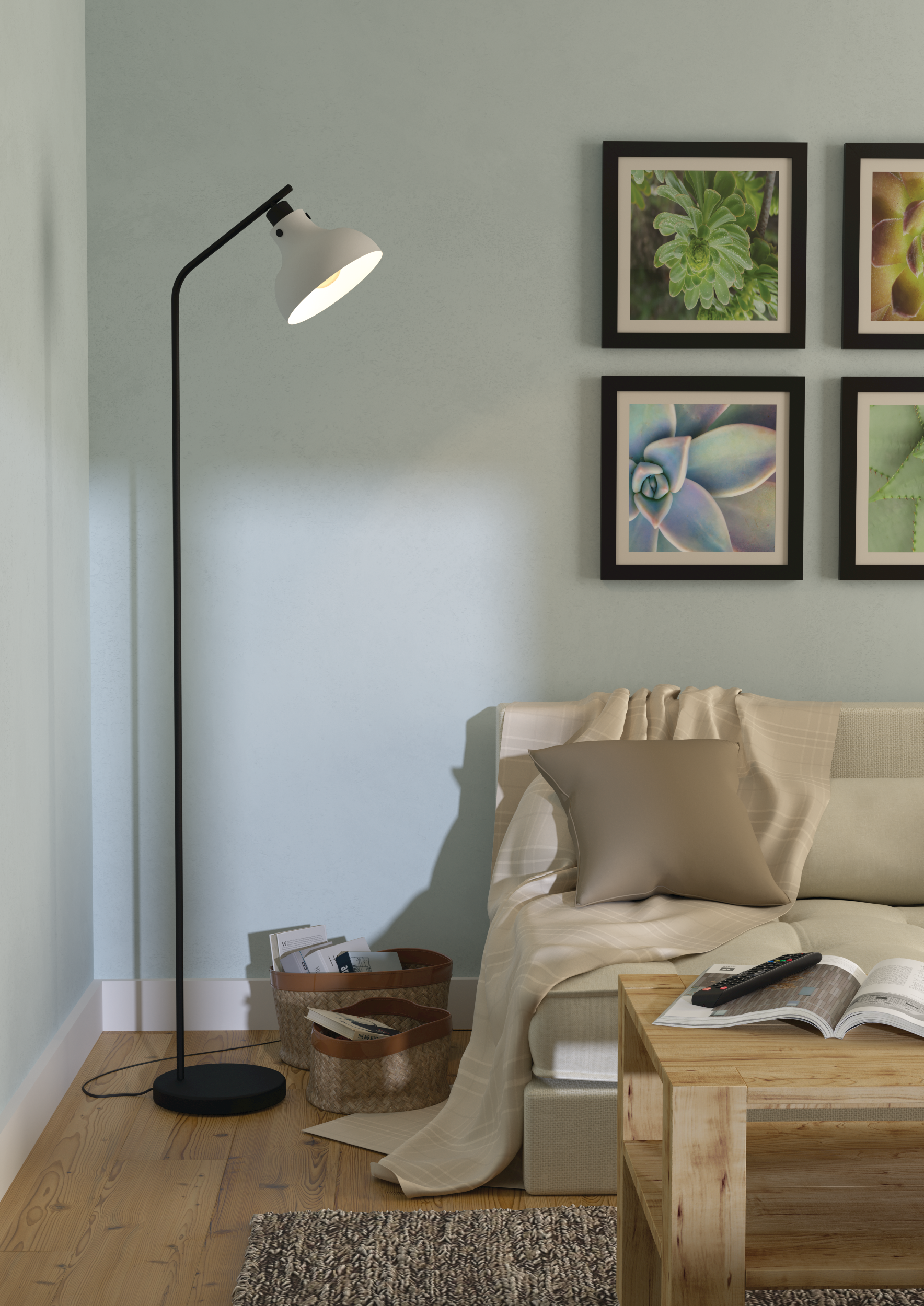 Ein Raum mit Stehlampe, Couch, Couchtisch und Bildern an der Wand. Bücher und Körbe liegen auf dem Boden.