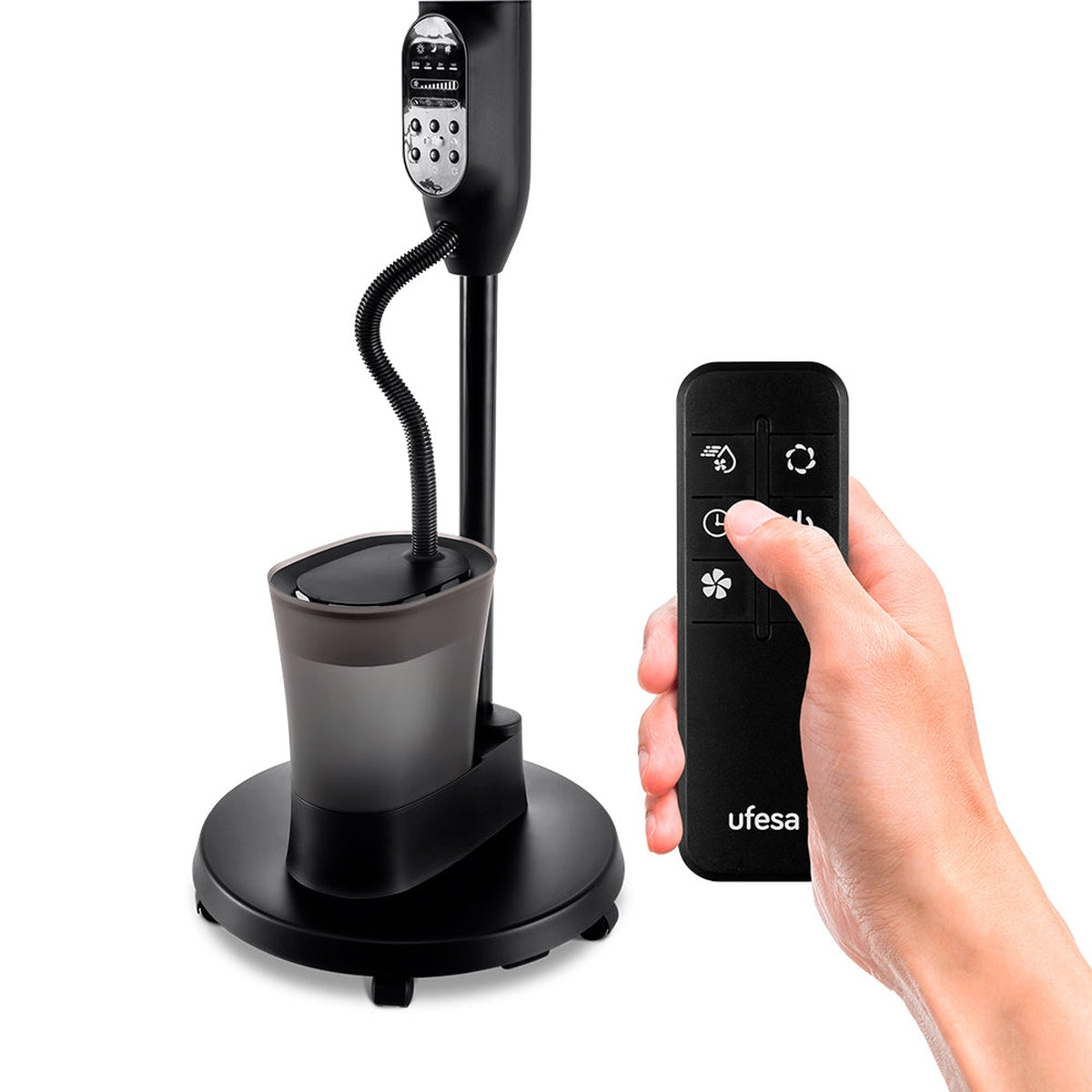 Humidificador negro con mando a distancia. Una mano sostiene el mando. El humidificador tiene base redonda, depósito de agua y panel de control.