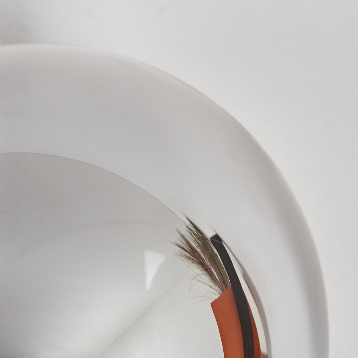 Ein glänzendes, silbernes, gekrümmtes Objekt, das die Umgebung reflektiert.