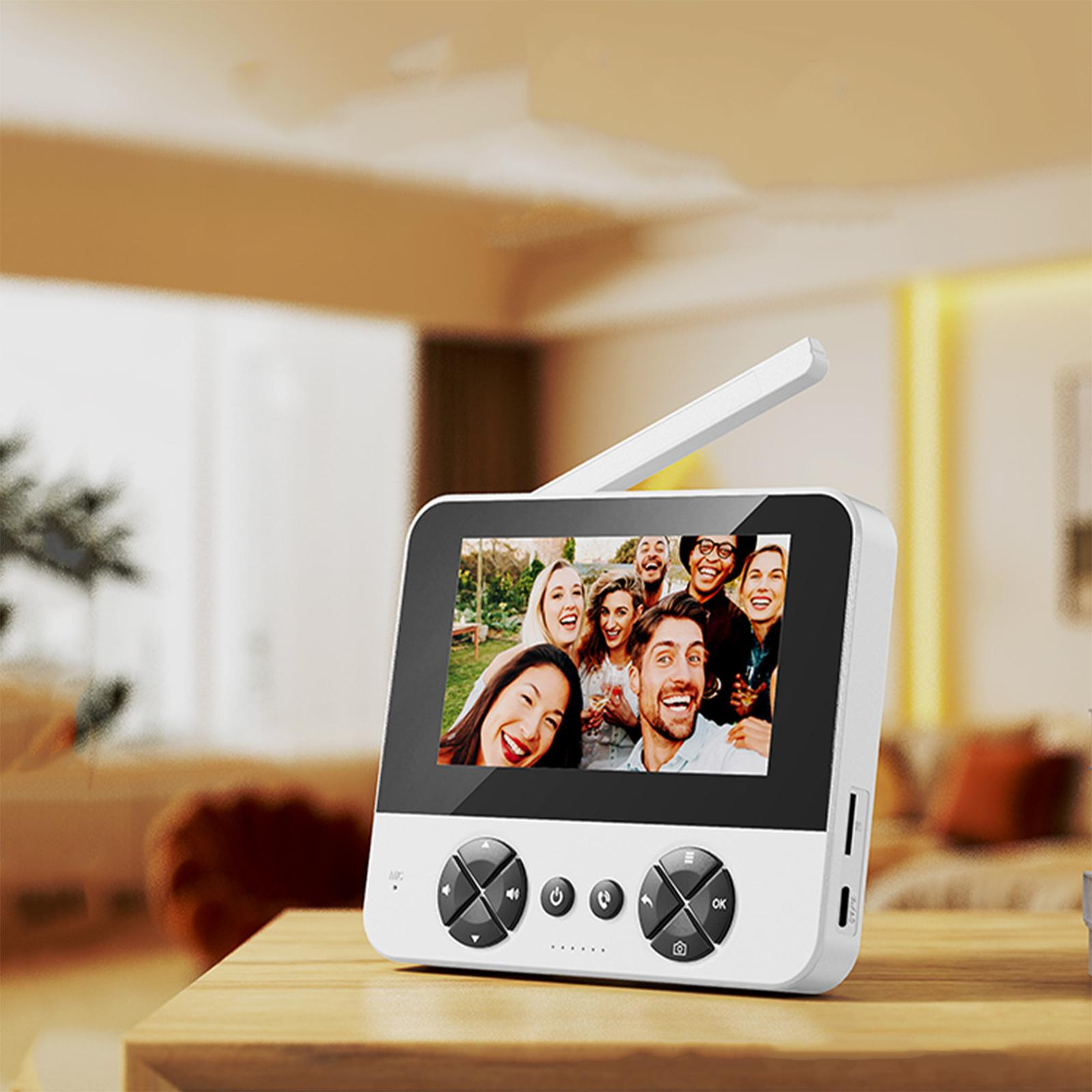 Ein Babyphone zeigt eine Gruppe von Personen. Der Monitor ist weiß und steht auf einem Tisch.
