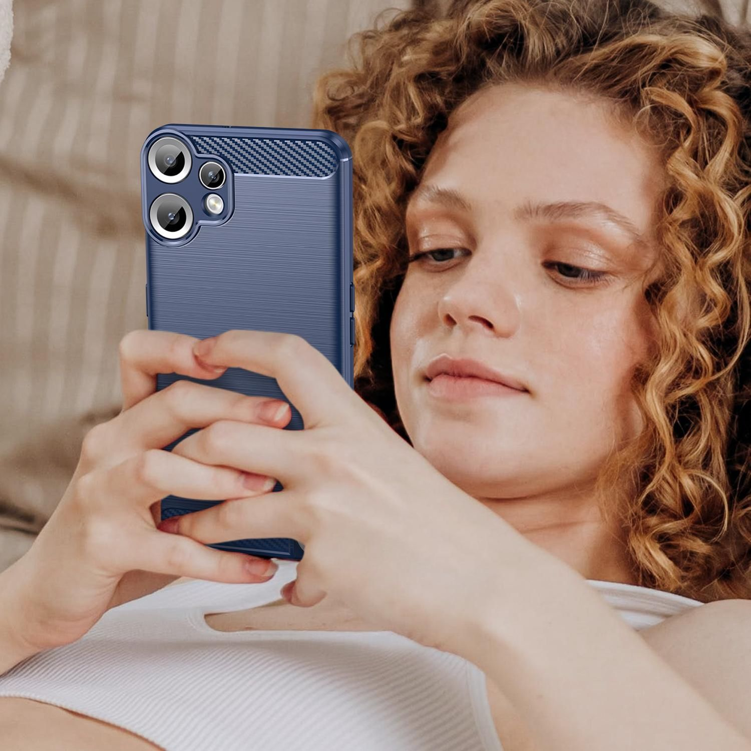 Eine Frau mit lockigem Haar benutzt ein blaues Telefon. Das Telefon hat mehrere Kameras. Sie schaut darauf hinab.