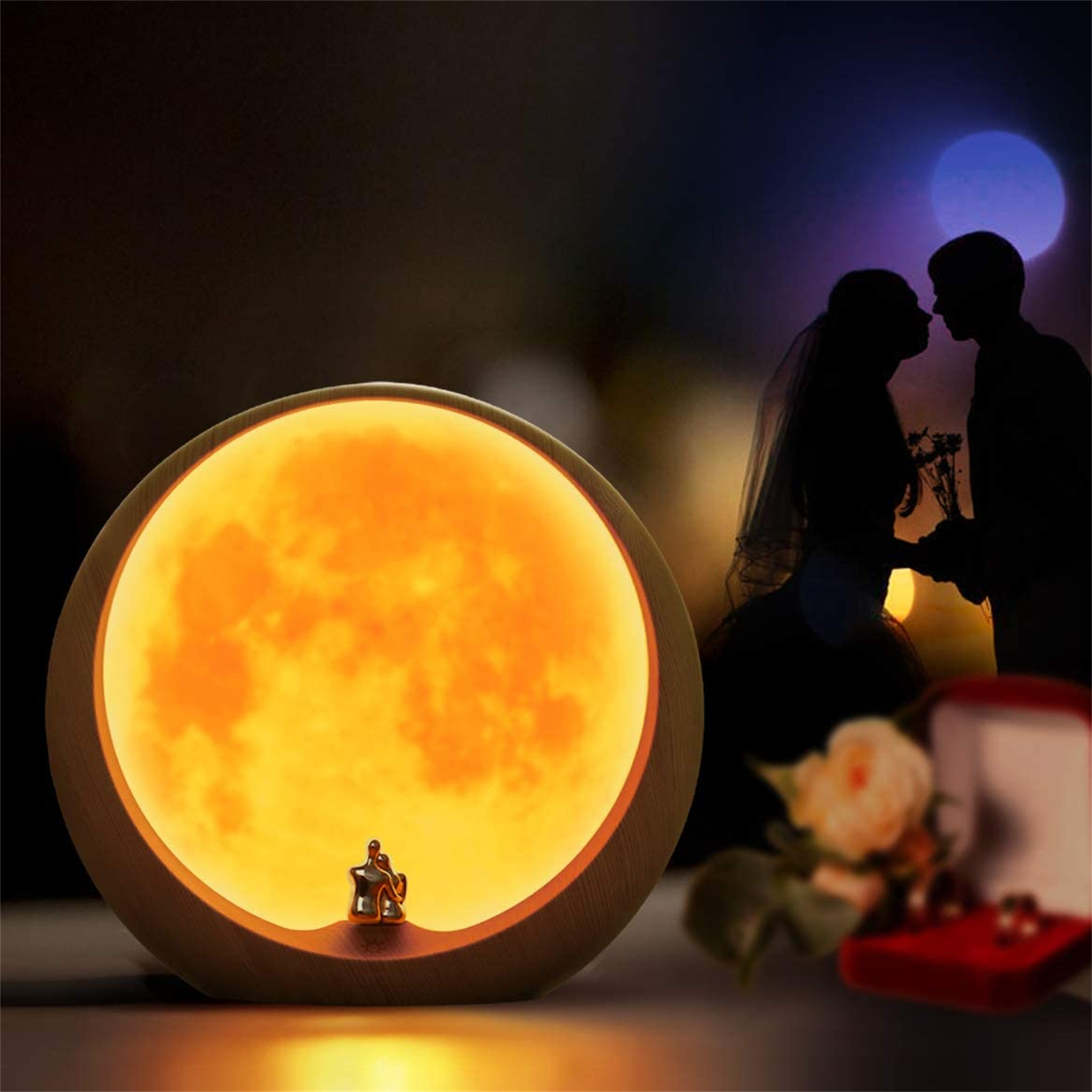 Eine mondförmige Lampe mit einer Figurenpaar, mit einer küssenden Paarsilhouette und einer Ringbox im Hintergrund.