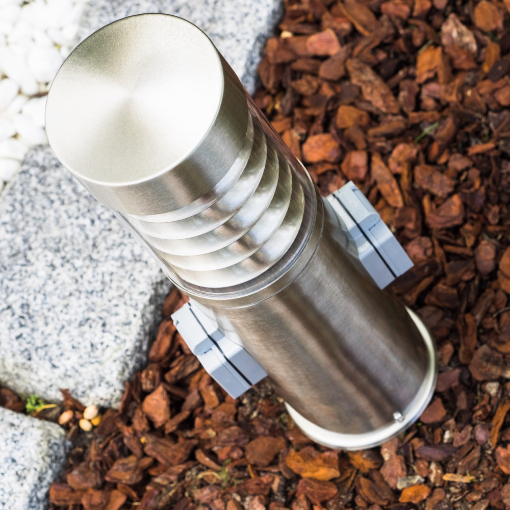 Eine Nahaufnahme von oben einer Edelstahl-Außenlampe mit Rinden- und Steingrund.