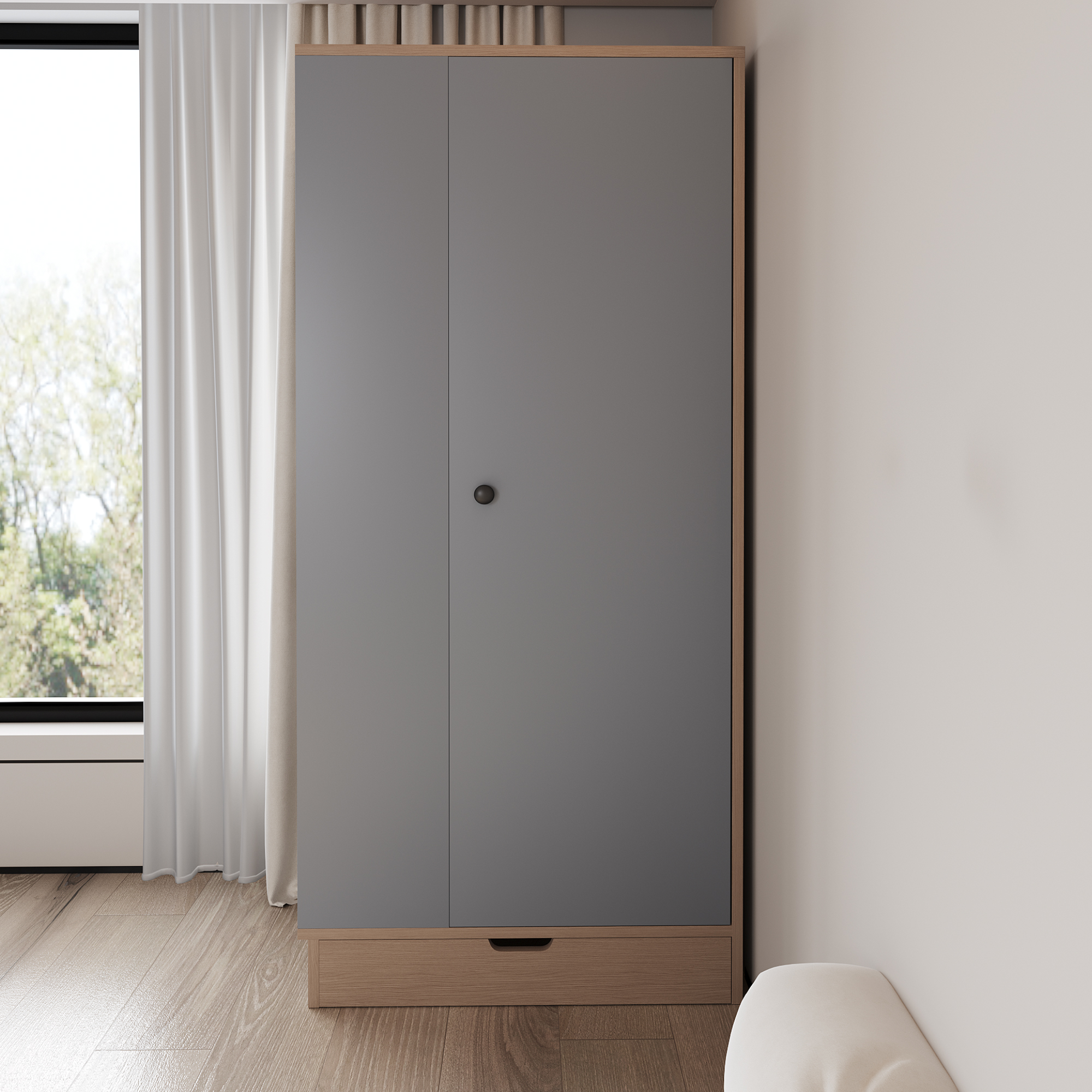 Ein grauer Kleiderschrank mit Holzsockel und Schublade. Die Tür ist geschlossen. Es gibt eine weiße Wand und ein Fenster in der Nähe.