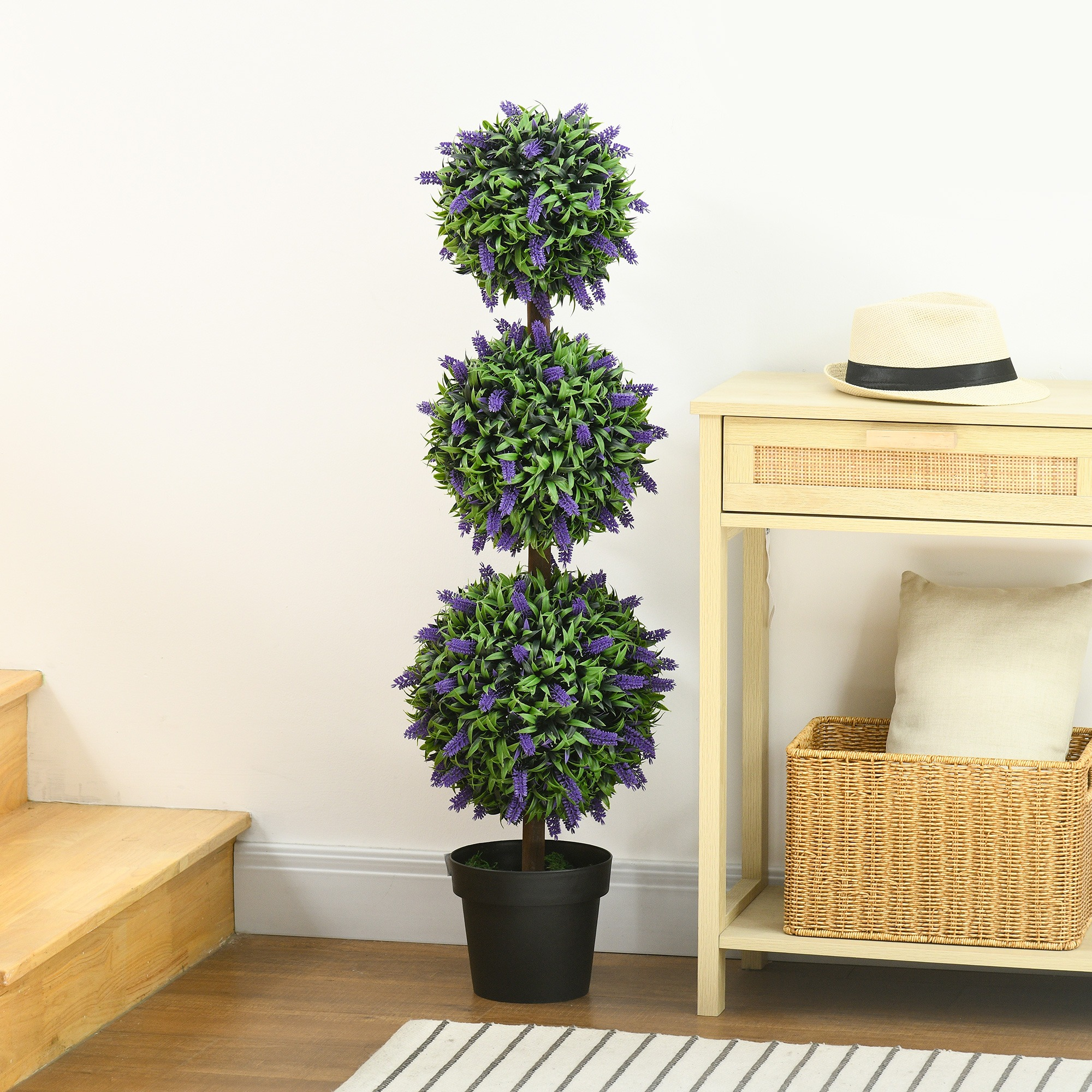 Eine dreistufige Topiary mit lila Blumen in einem schwarzen Topf steht in einem Raum mit Tisch und Treppe.