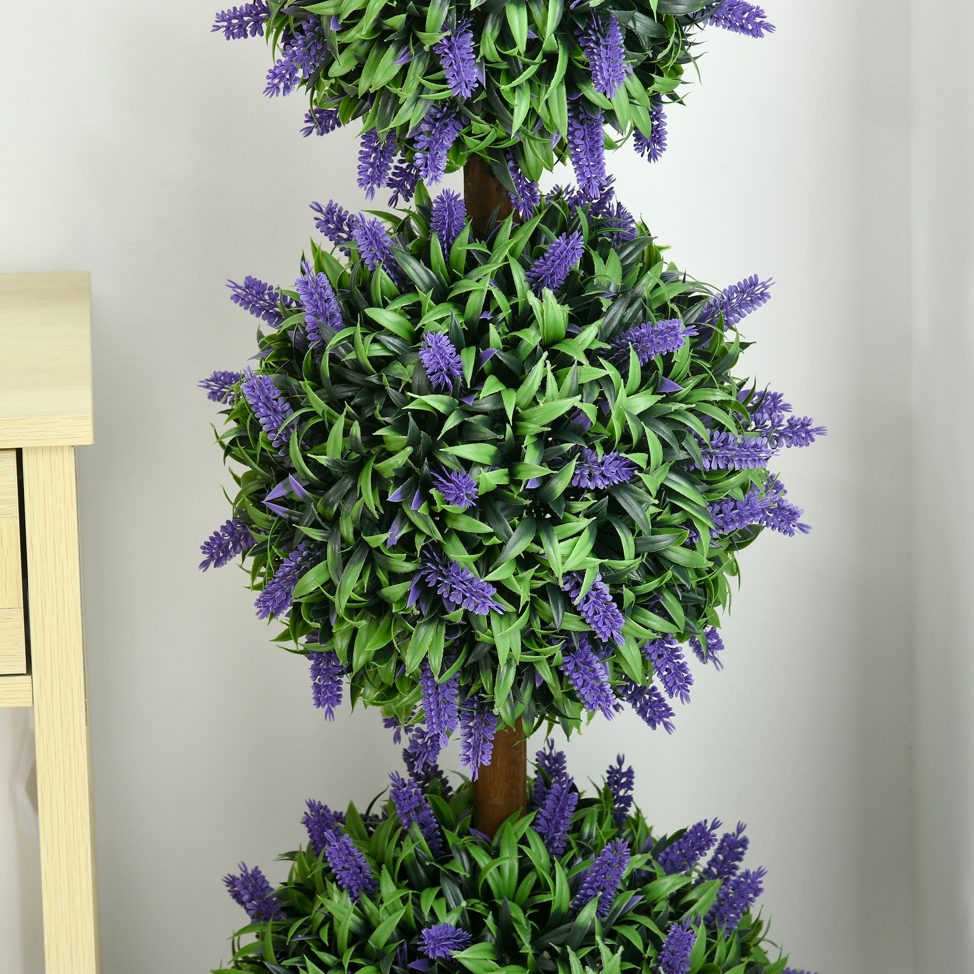 Nahaufnahme eines dreistufigen Lavendel-Topiaries mit lila Blüten und grünen Blättern.