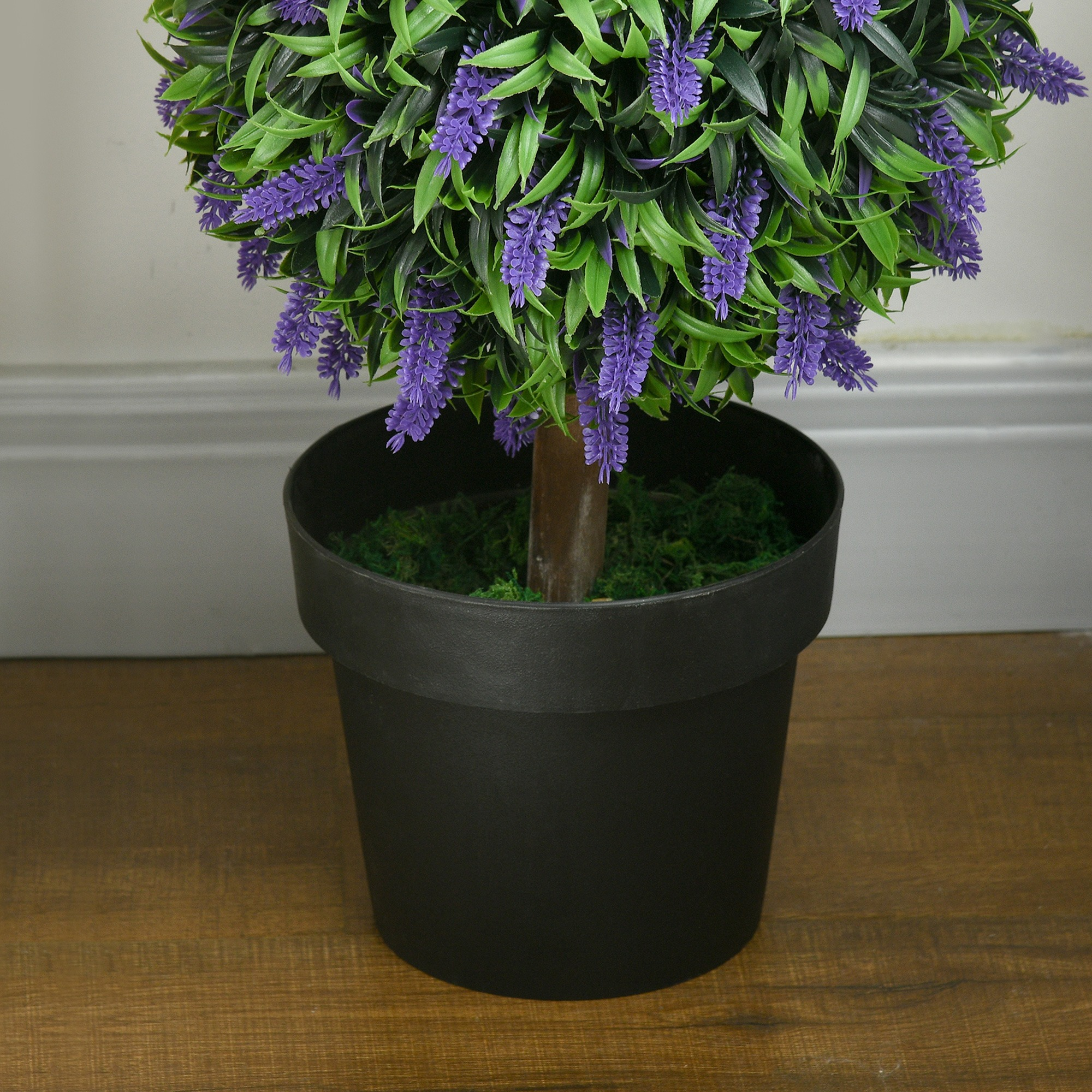 Ein getopfter Lavendel-Topiari auf einem Holzboden. Die Pflanze hat lila Blüten und grüne Blätter.