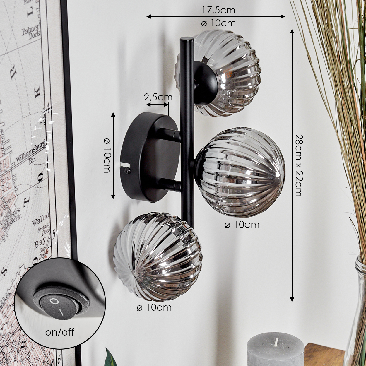 Eine Wandlampe mit drei Glaskugeln, schwarzem Rahmen und in cm beschrifteten Maßen.