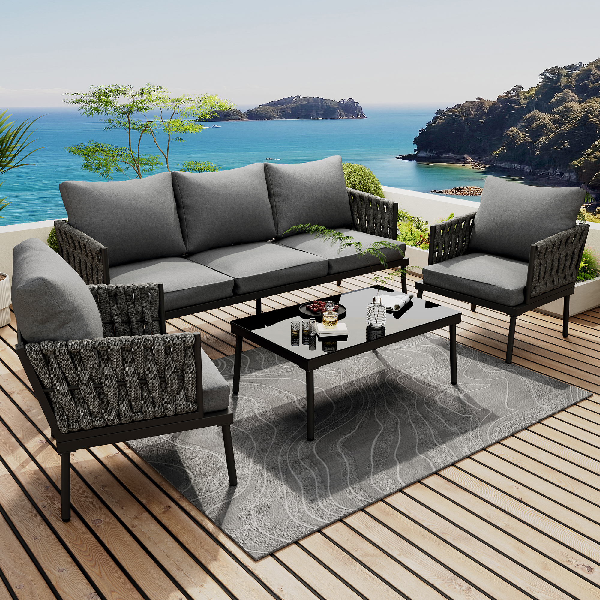 Outdoor-Terrassenset mit Sofa, zwei Sesseln und einem Tisch, mit Blick auf das Meer. Graue Kissen und schwarze Rahmen.