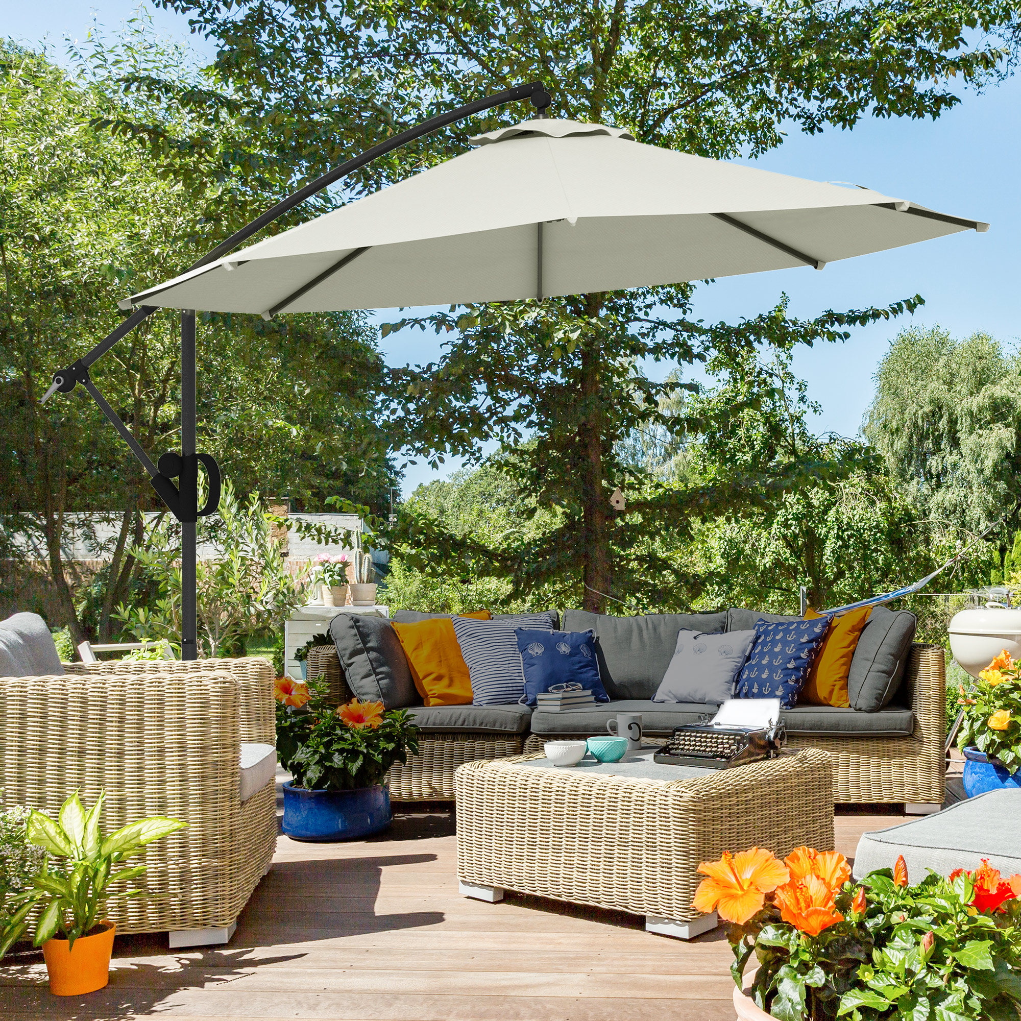 Un patio con mobili da esterno sotto un ombrellone beige aperto in una giornata di sole.