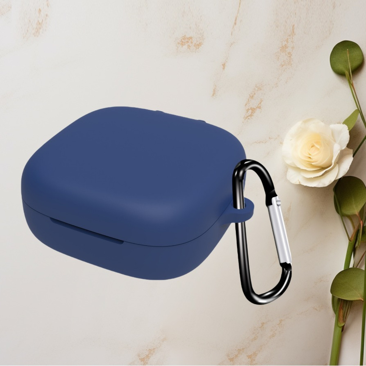 Custodia per auricolari blu navy con un moschettone nero. Una rosa bianca e foglie verdi sullo sfondo.