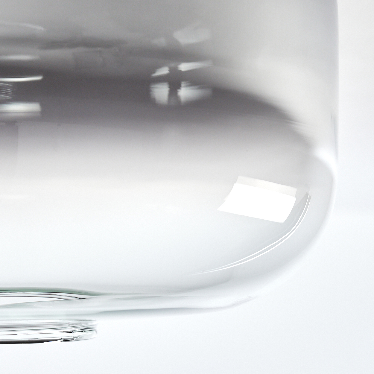 Nahaufnahme einer Deckenleuchte aus Glas, die den gebogenen Rand des Glasschirms zeigt.