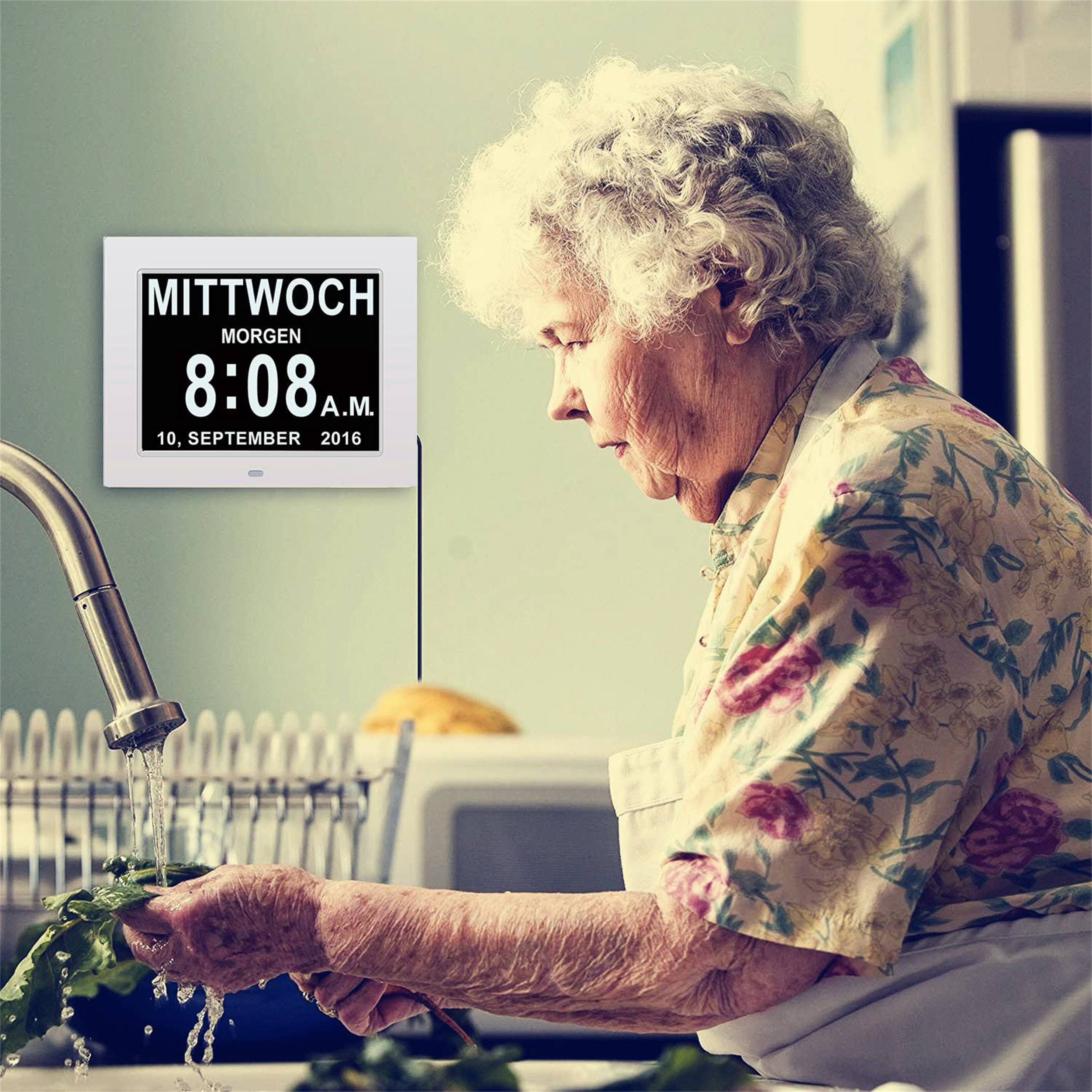 Eine ältere Frau, die in einer Küche Geschirr wäscht, eine Digitaluhr an der Wand.