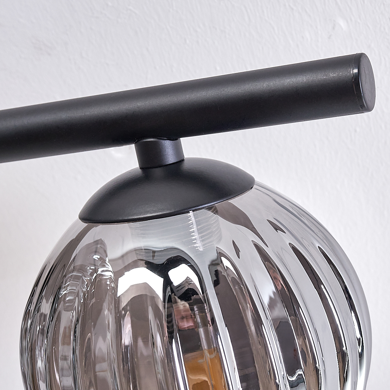 Nahaufnahme einer schwarzen Lampe mit geriffelter, verspiegelter Glaskugel. Die Glühbirne ist sichtbar.