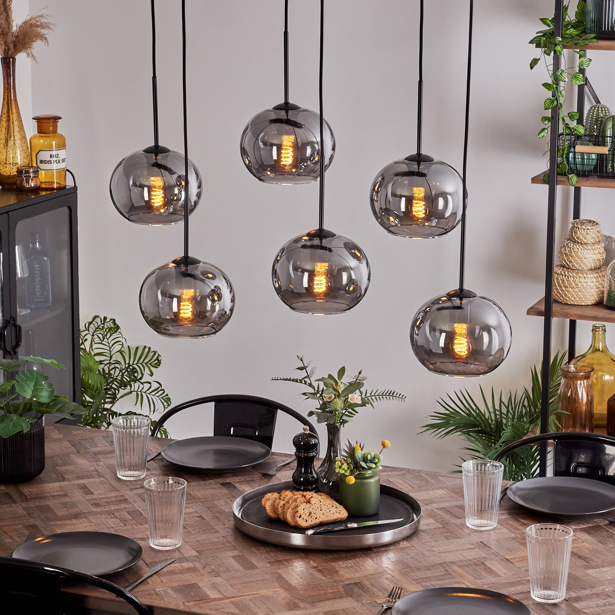 Ein Esszimmer mit einem Holztisch und sechs hängenden Pendelleuchten aus Chromkugeln.