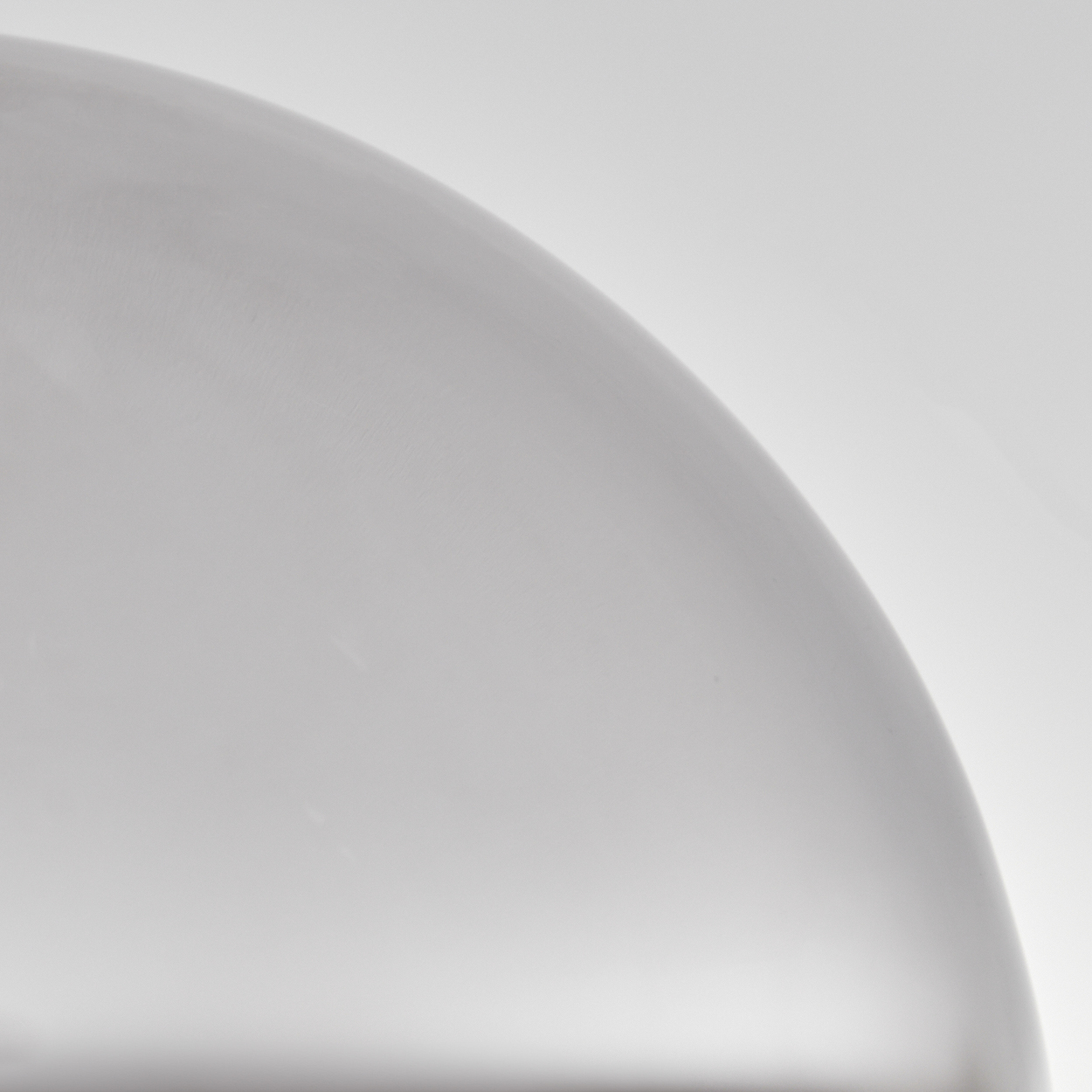 Nahaufnahme eines transparenten, gebogenen Glasobjekts, möglicherweise ein Lampenschirm.