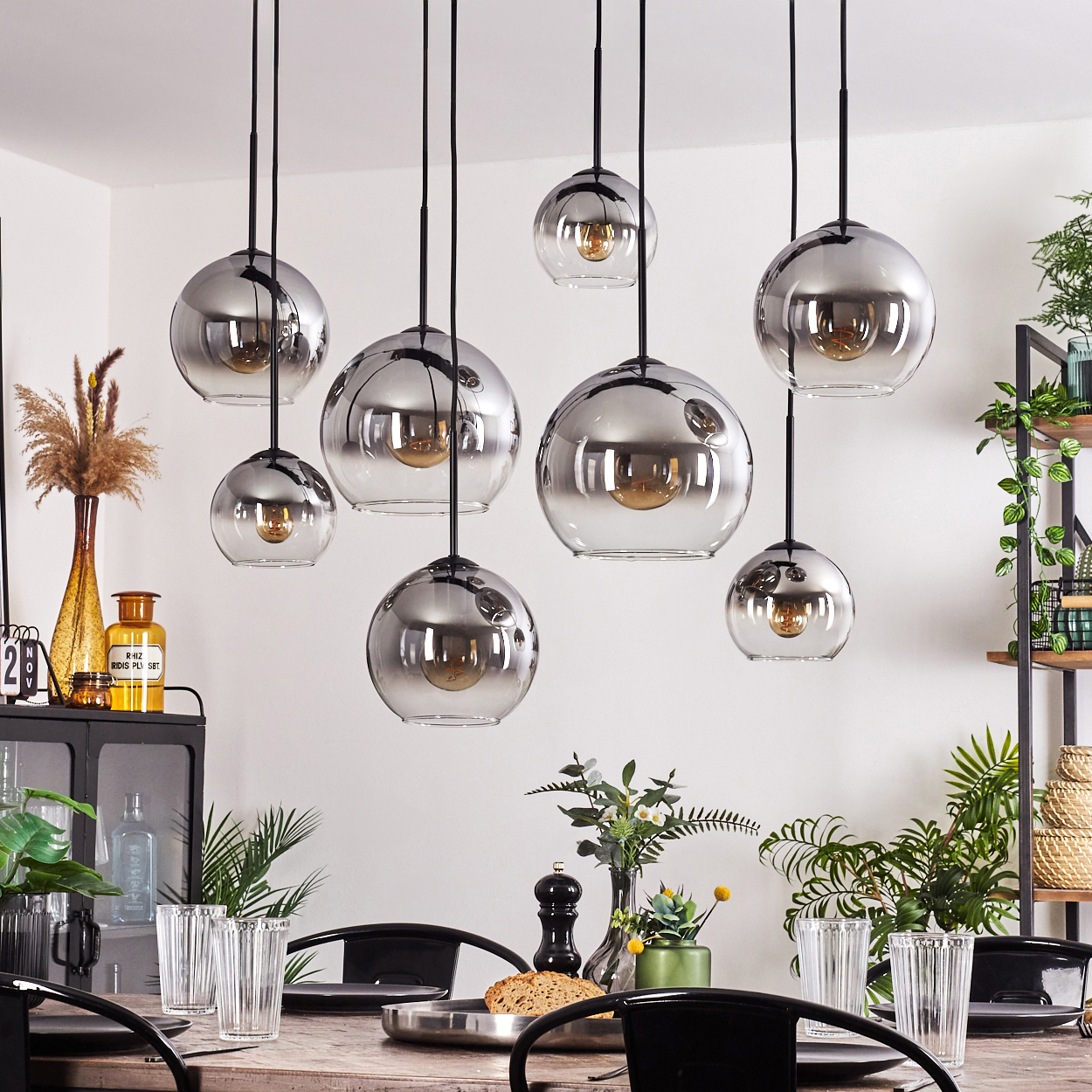 Esszimmer mit mehreren Hängelampen mit Glasschirmen und Wendelglühbirnen.