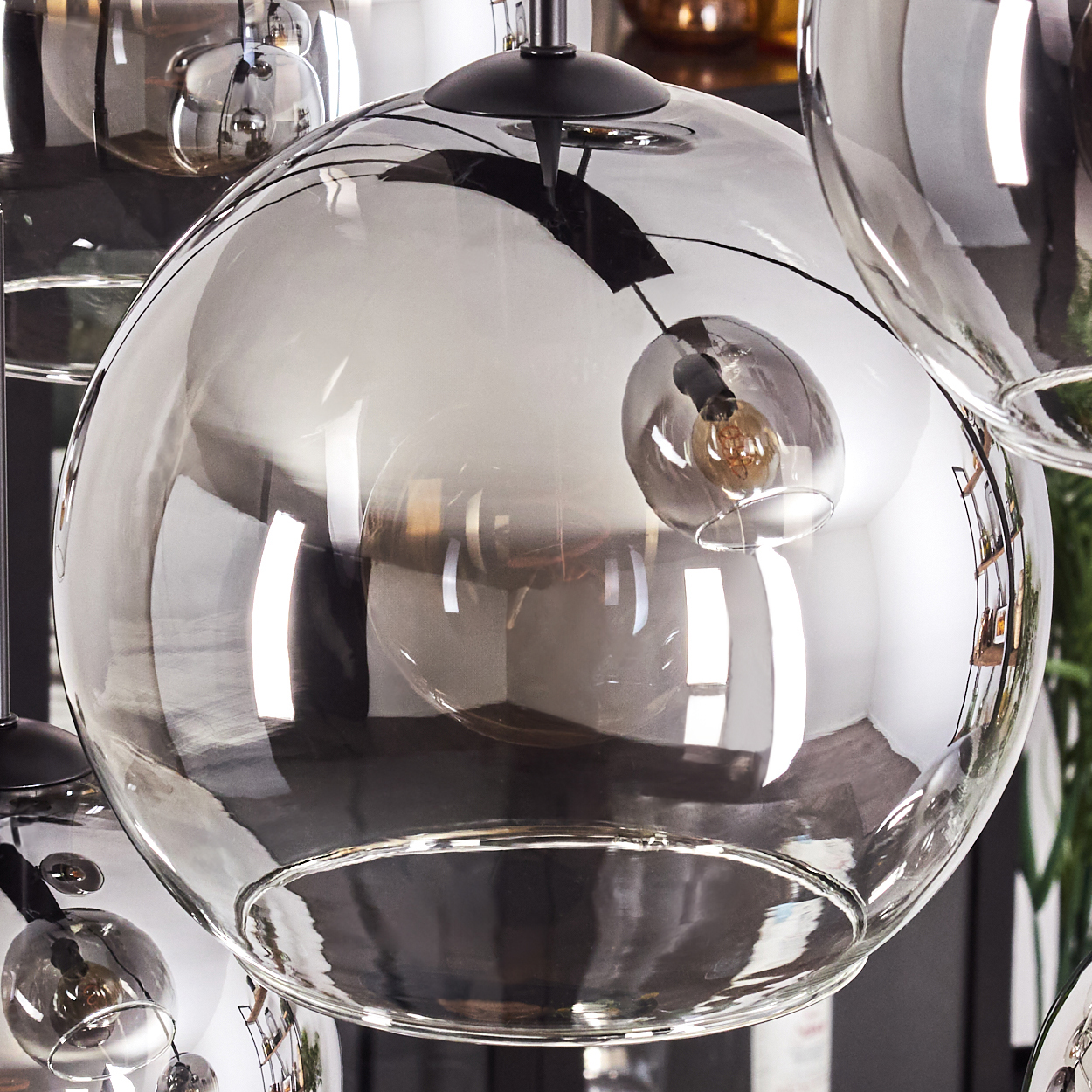Nahaufnahme einer Glaskugellampe mit Glühbirne, die die Umgebung reflektiert.