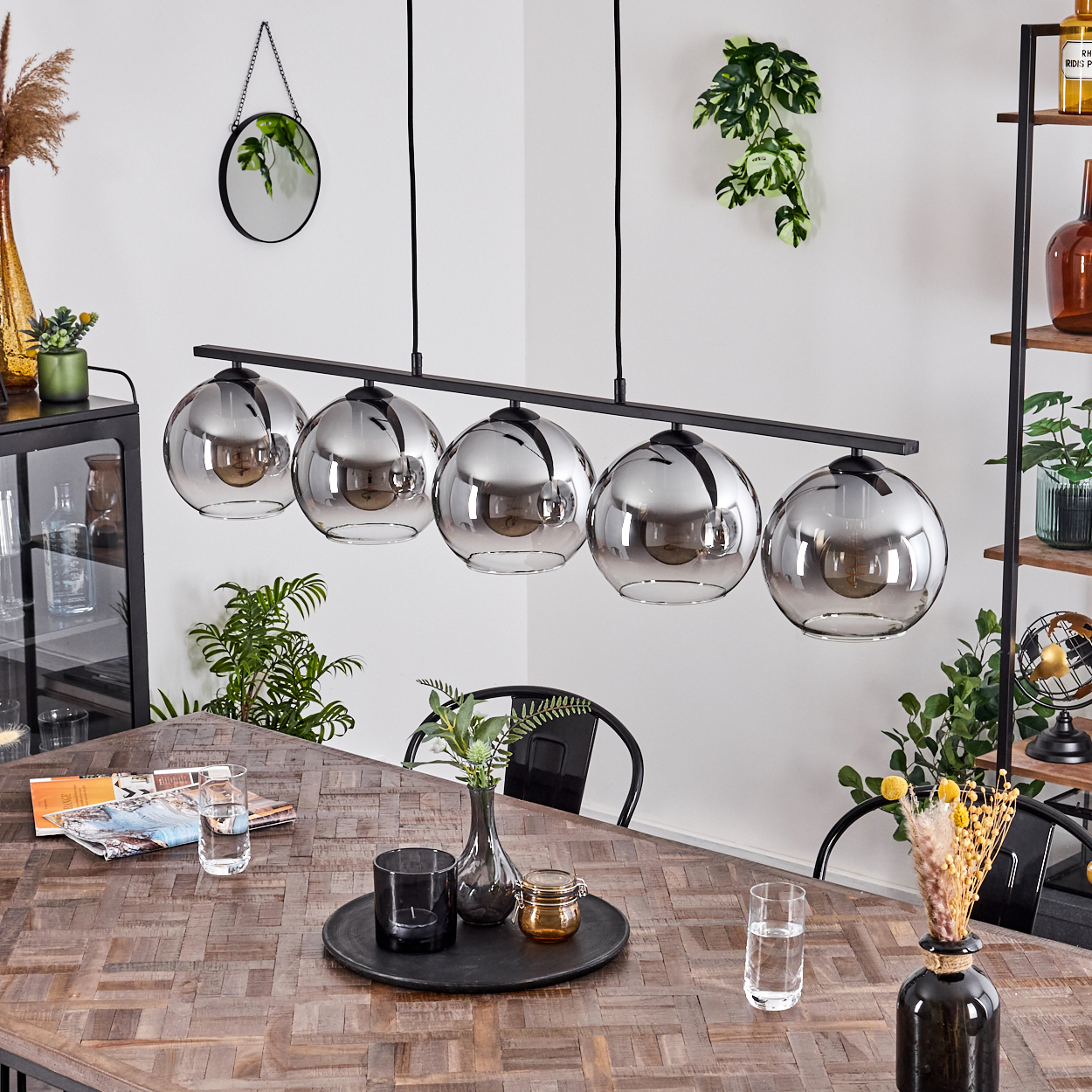 Esszimmer mit Holztisch, schwarzer linearer Leuchte und verschiedenen Dekorationselementen.