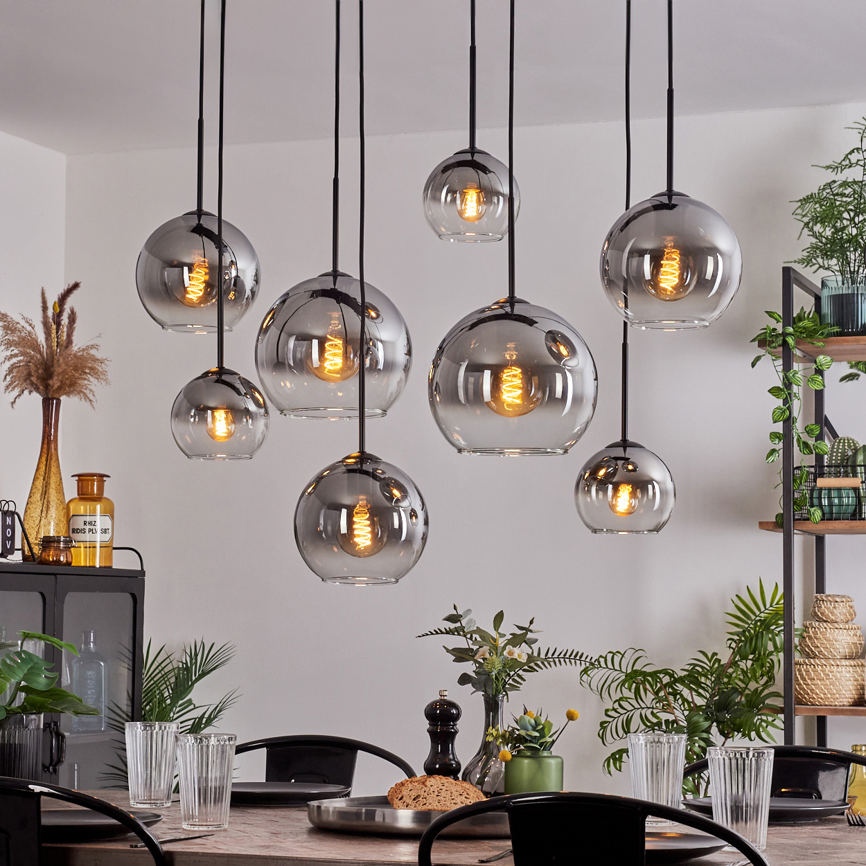 Esszimmer mit mehreren Hängelampen mit Glasschirmen und Wendelglühbirnen.