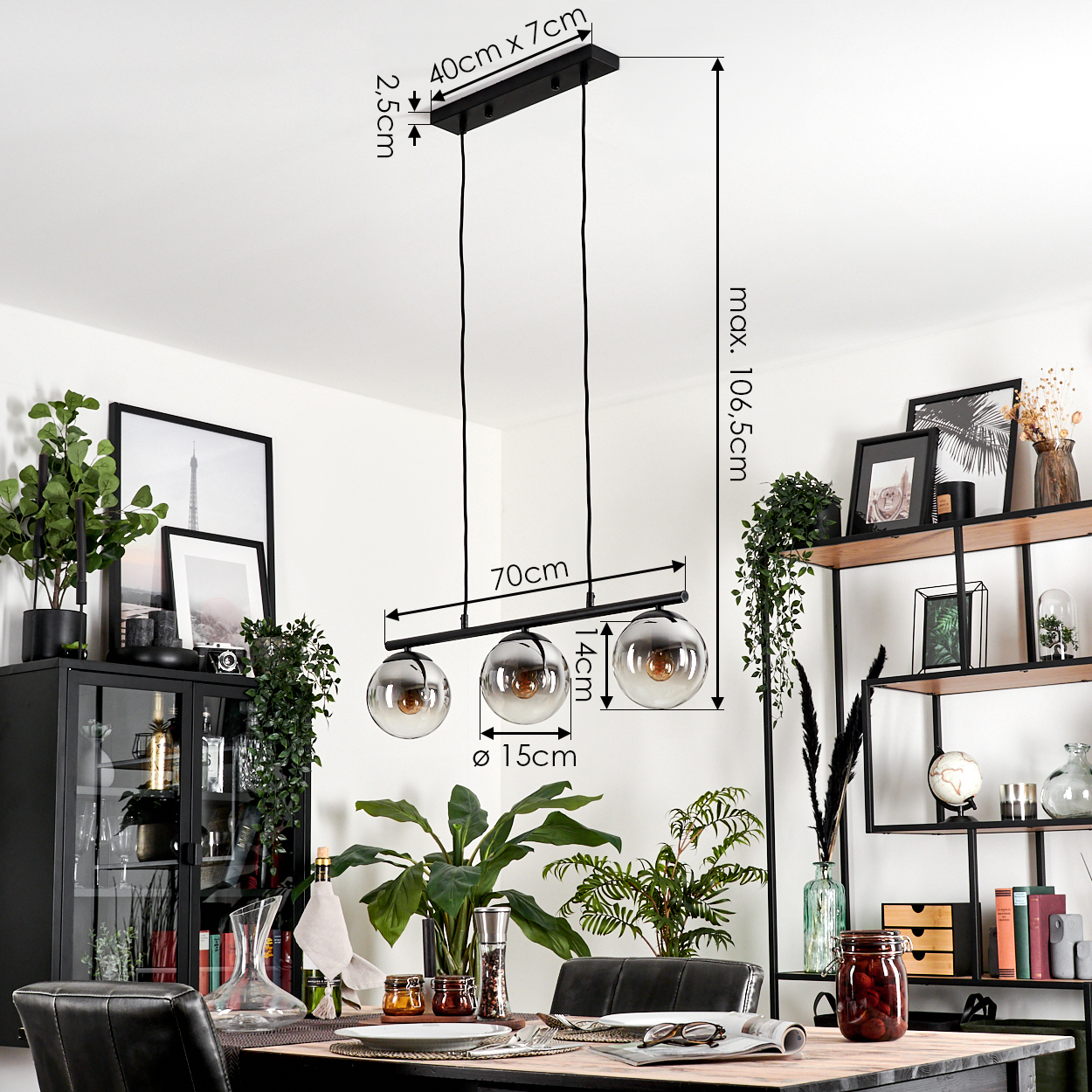 Ein Esszimmer mit einem Kronleuchter mit drei rauchigen Glaskugeln. Ein Tisch ist mit Pflanzen und Dekor gedeckt.
