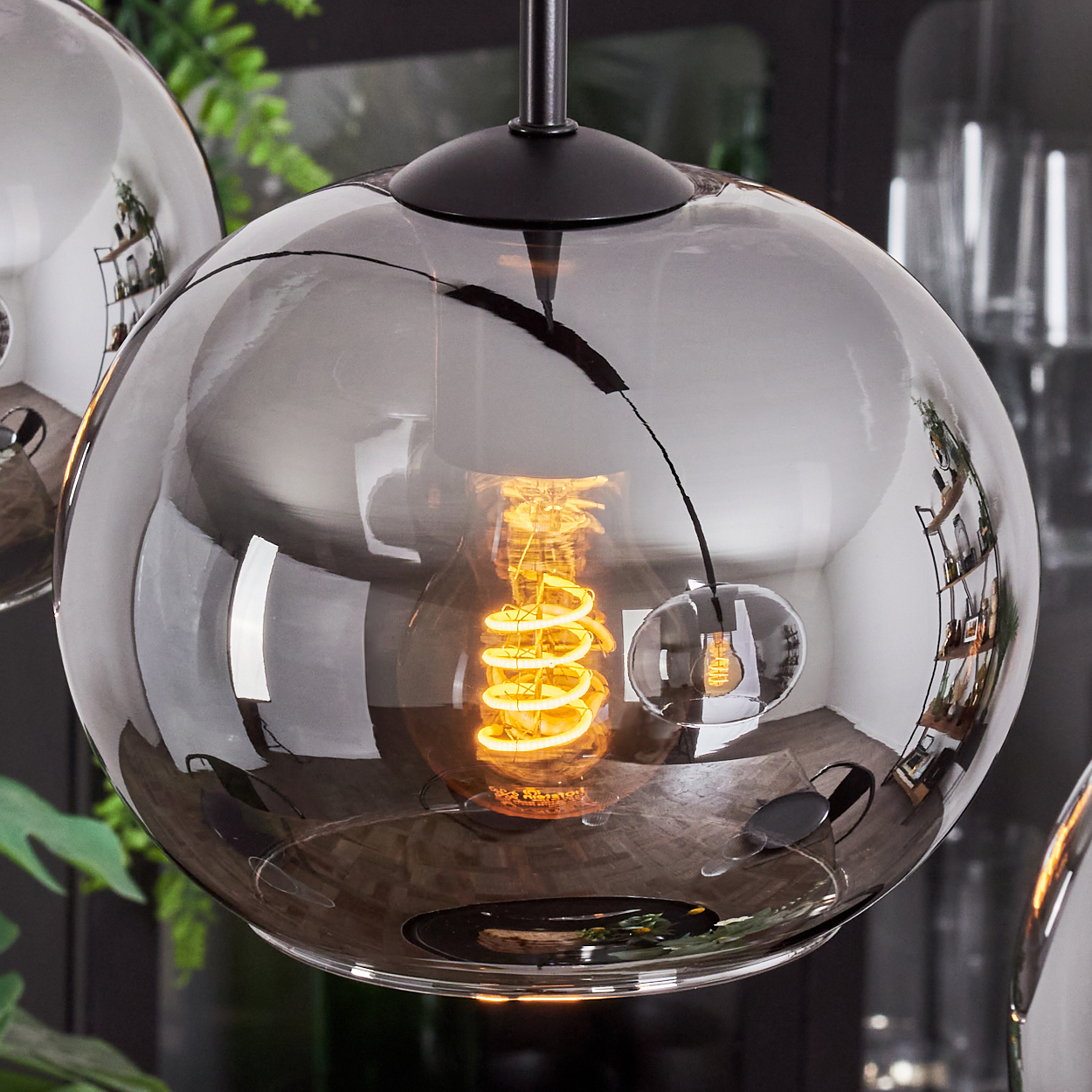 Nahaufnahme eines rauchigen Glaskugel mit einer leuchtenden, spiralförmigen Glühbirne. Die Leuchte ist Teil eines modernen Lichtdesigns.