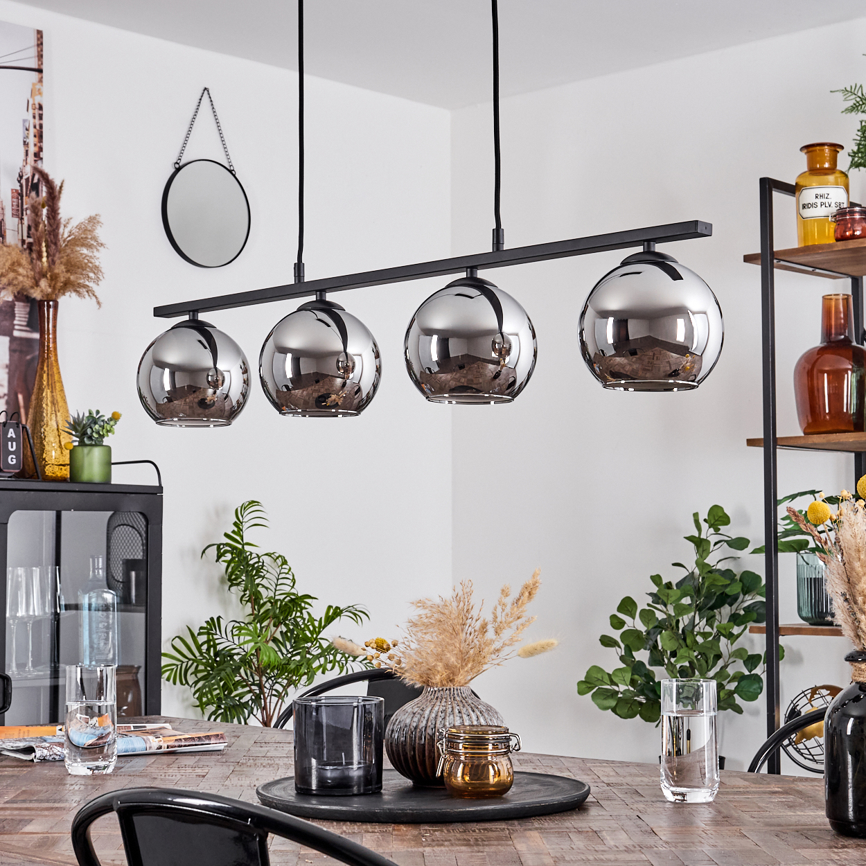 Esszimmer mit vier Kugel-Pendelleuchten, Holztisch und Dekorationsartikeln, einschließlich eines Spiegels.