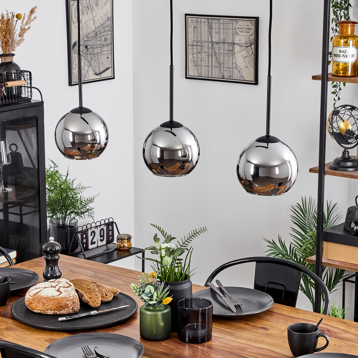 Ein Esszimmer mit einem Holztisch, drei Hängelampen und einem Regal mit Dekoration.