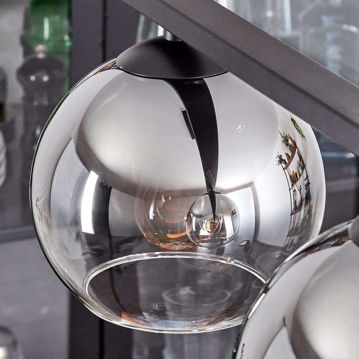 Nahaufnahme einer bauchigen Pendelleuchte mit klarem Glasschirm, die die Glühbirne im Inneren zeigt.