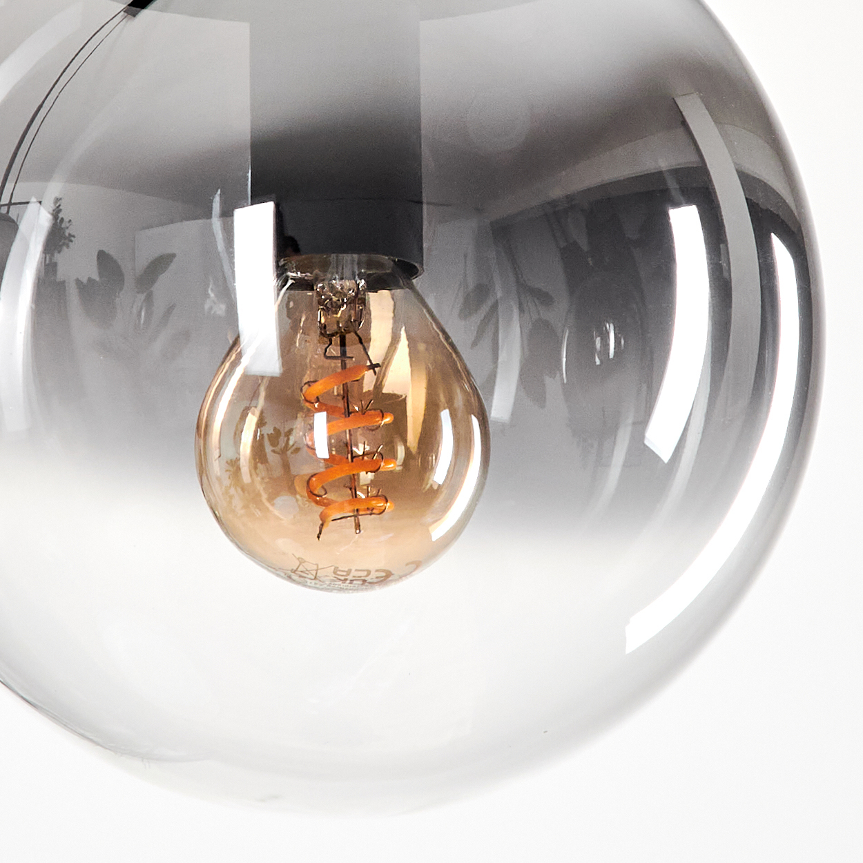 Nahaufnahme einer Glühbirne in einem Globus. Die Glühbirne ist an. Der Globus ist transparent.