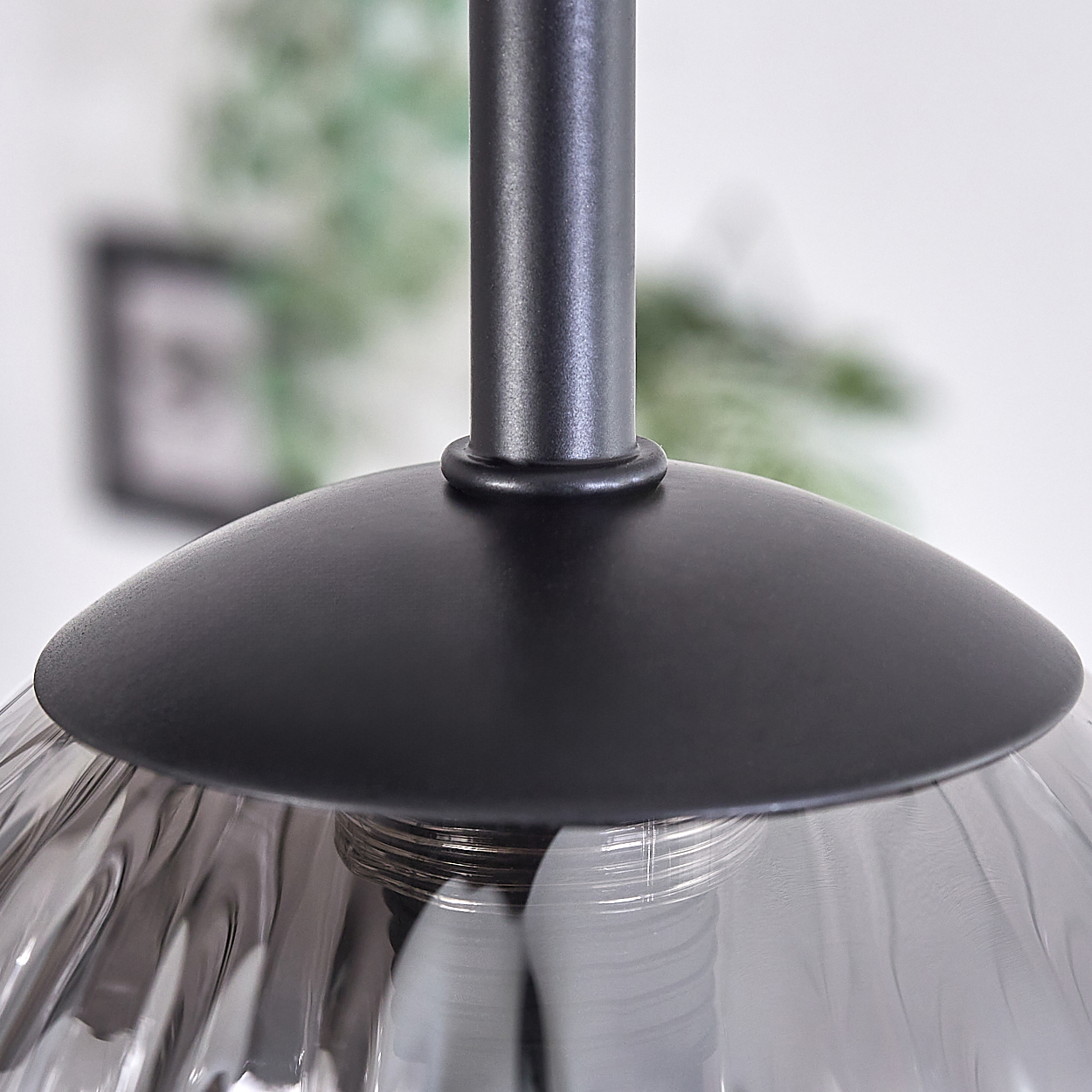 Nahaufnahme einer schwarzen Fassung mit einem rauchfarbenen Glasschirm, die den Anschluss an die Glühbirne und ihre Halterung zeigt.