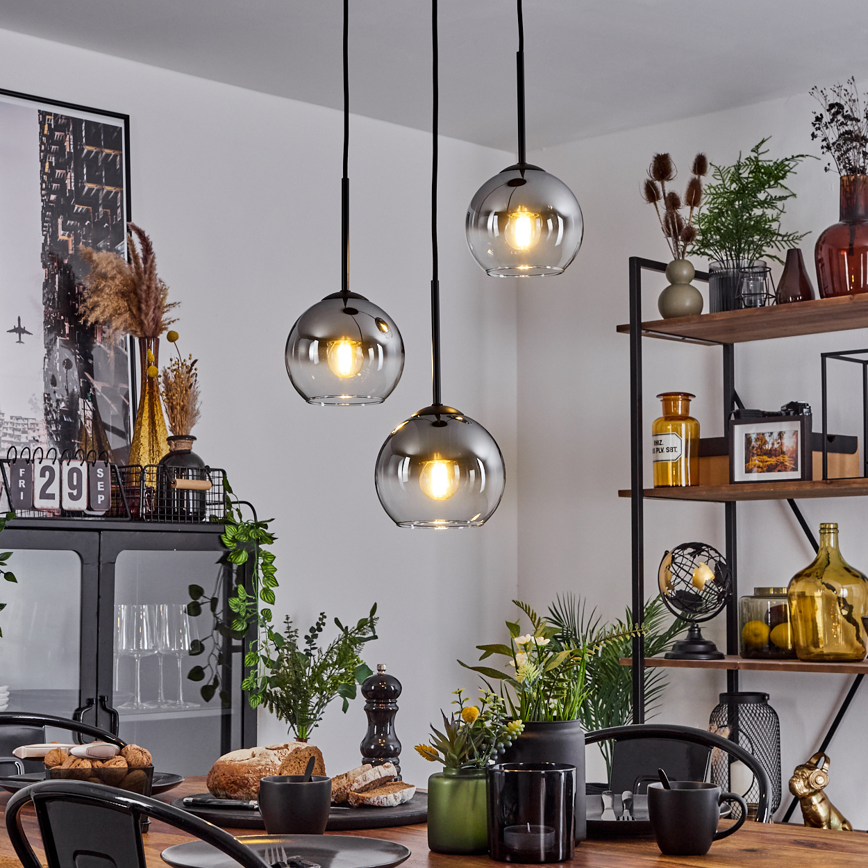 Esszimmer mit drei Glaskugel-Pendelleuchten. Tisch mit Brot und Kaffeetassen.