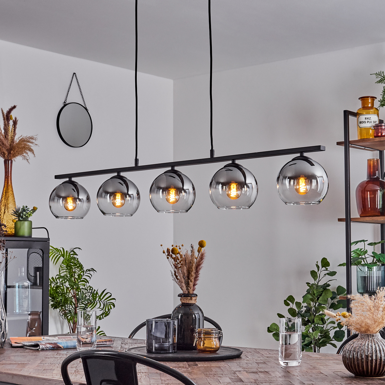 Ein Esszimmer mit Kronleuchter mit 5 kugelförmigen Lampen. Der Tisch ist gedeckt, und es gibt dekorative Elemente.