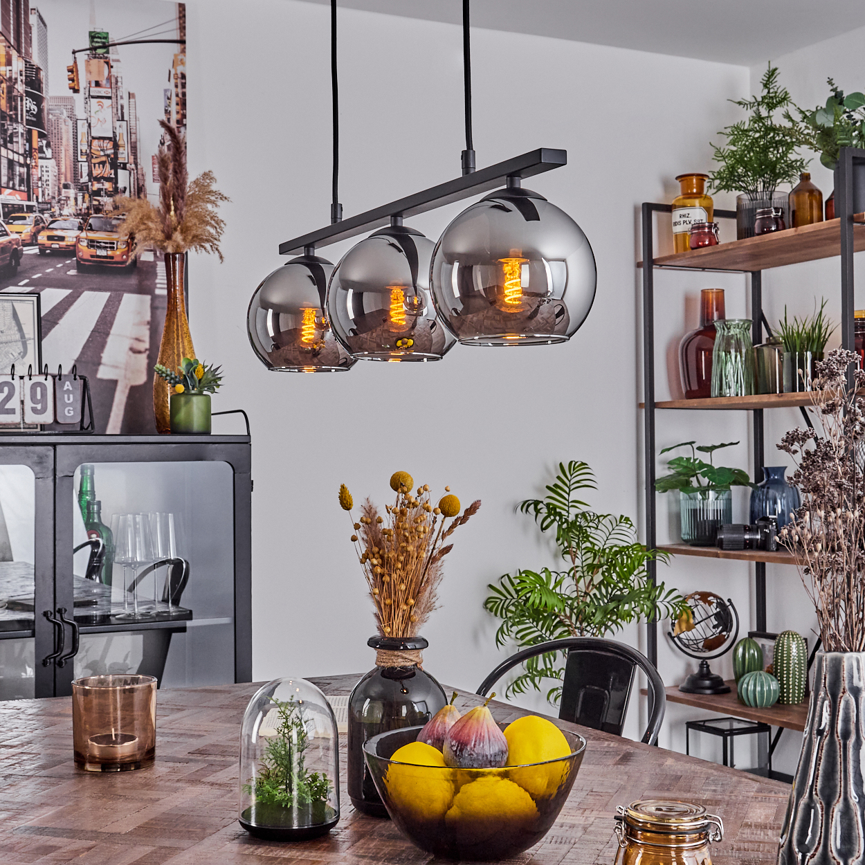 Esszimmer mit drei silbernen Kugelleuchten, Holztisch und Dekorationsartikeln.