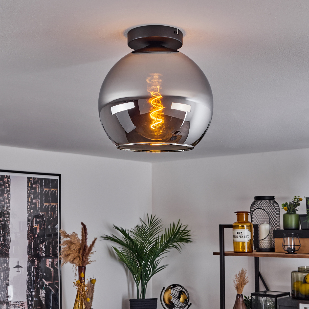 Deckenlampe mit silbernem Globus, Spirallampe und weißer Decke.