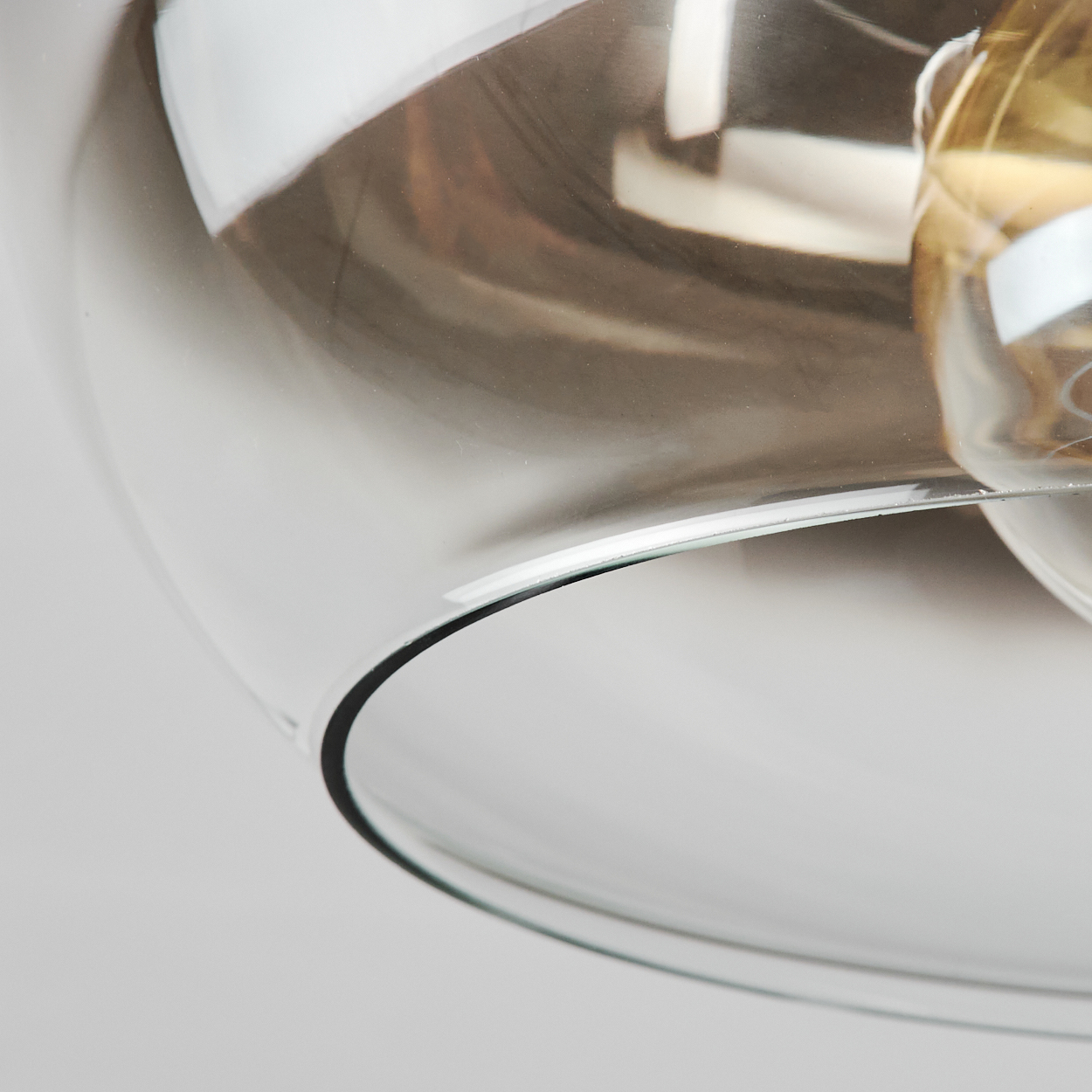 Nahaufnahme einer Glas-Pendelleuchte, die die warme Glühbirne mit sichtbar spiralförmigem Glühfaden zeigt.