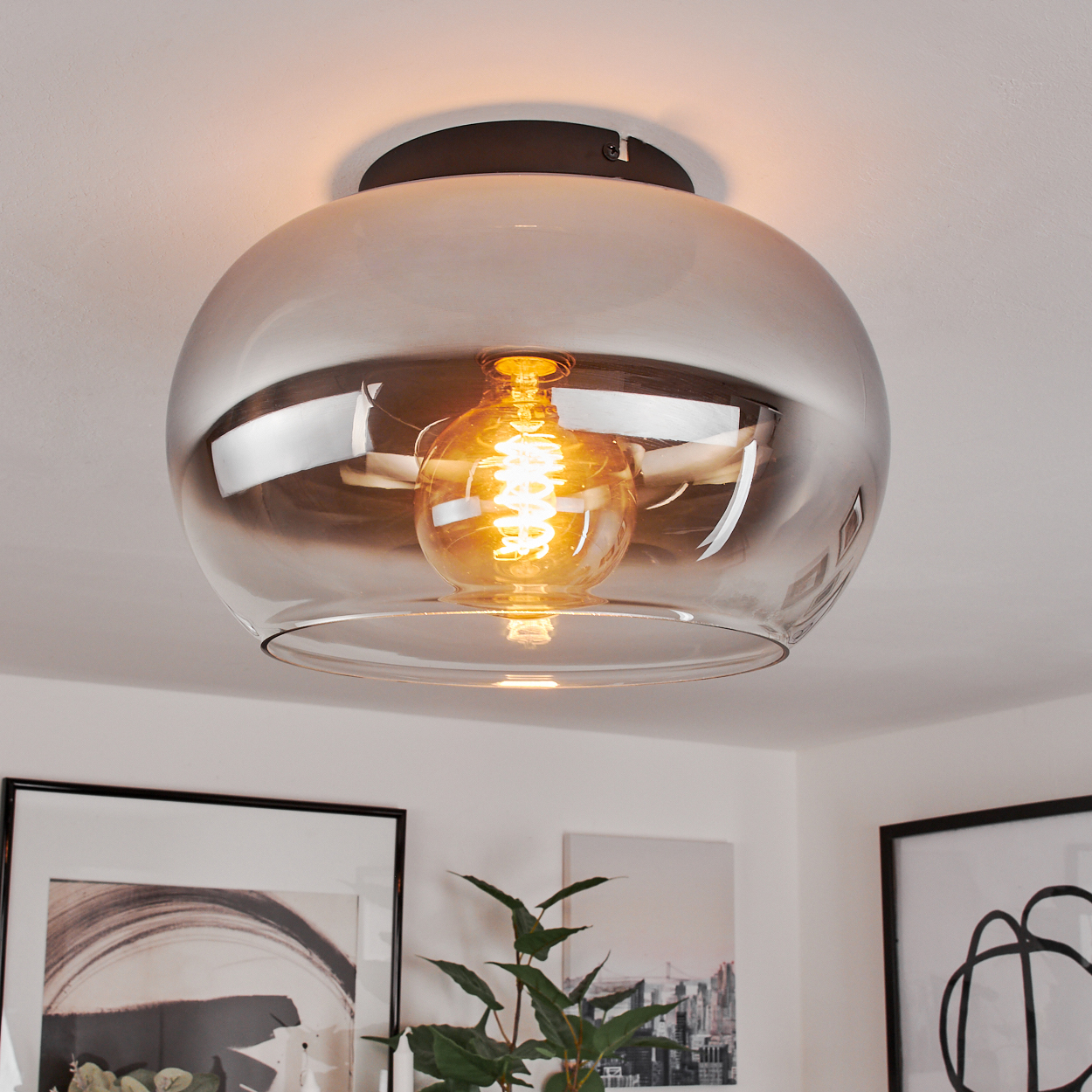 Eine einzelne Pendelleuchte mit Glasschirm und warmer Glühbirne hängt von einer weißen Decke.