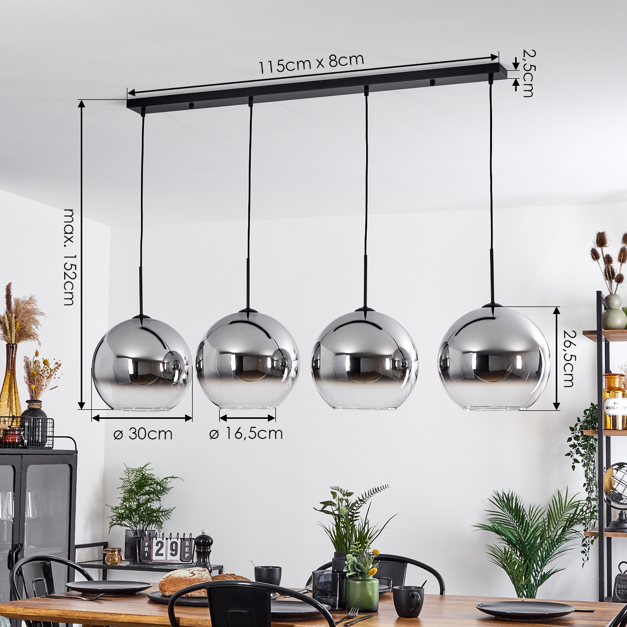 Esszimmer mit Pendelleuchten mit silbernen Kugeln und Wendelbirnen. Tisch mit Gläsern und Brot gedeckt.