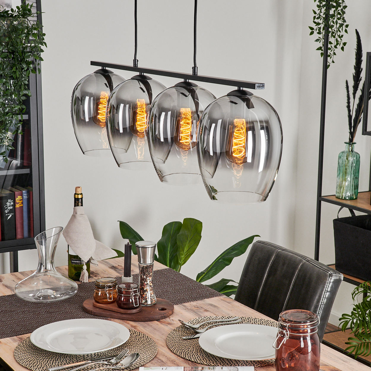 Ein Esszimmer mit Tisch, Dekorationen und vier Pendelleuchten mit Glasschirmen.