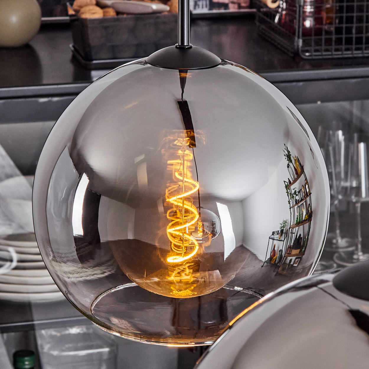Nahaufnahme einer Glühbirne in einem abgerundeten Glasschirm, der Hintergrund ist unscharf.