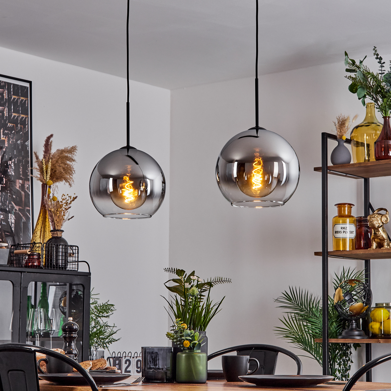 Zwei Pendelleuchten mit verspiegelten Kugeln hängen in einem Raum. Die Lichter reflektieren den Inhalt des Raumes.