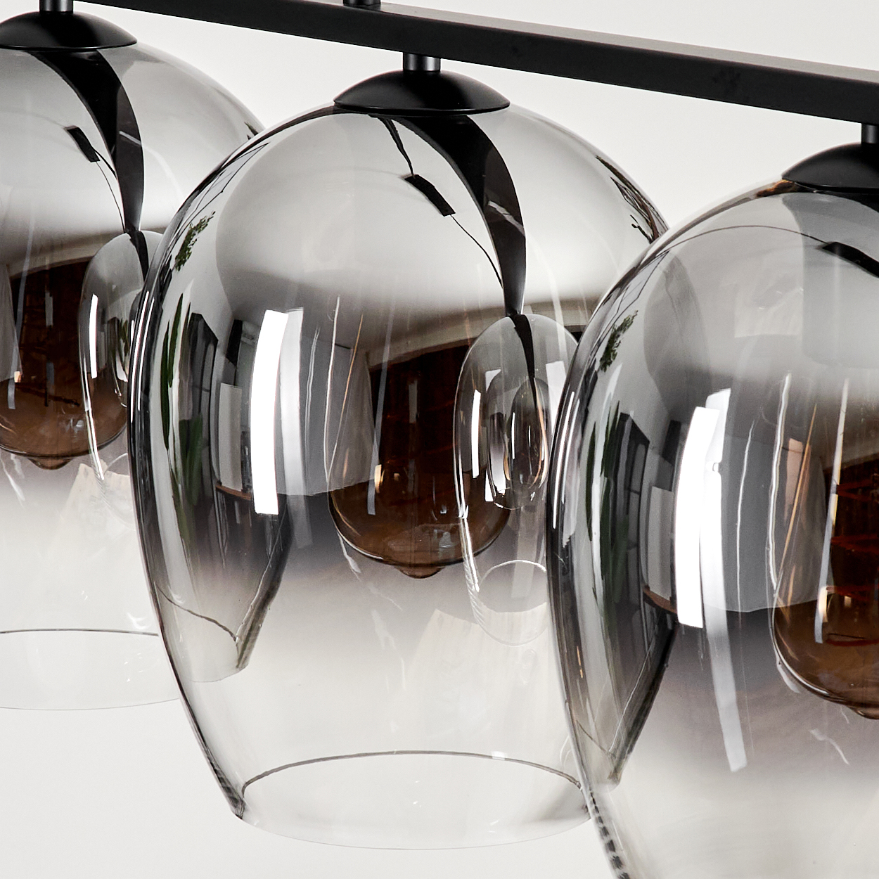 Nahaufnahme von Hängelampen mit Glasschirmen, Glühbirnen sichtbar. Die Schirme sind klar und reflektierend.