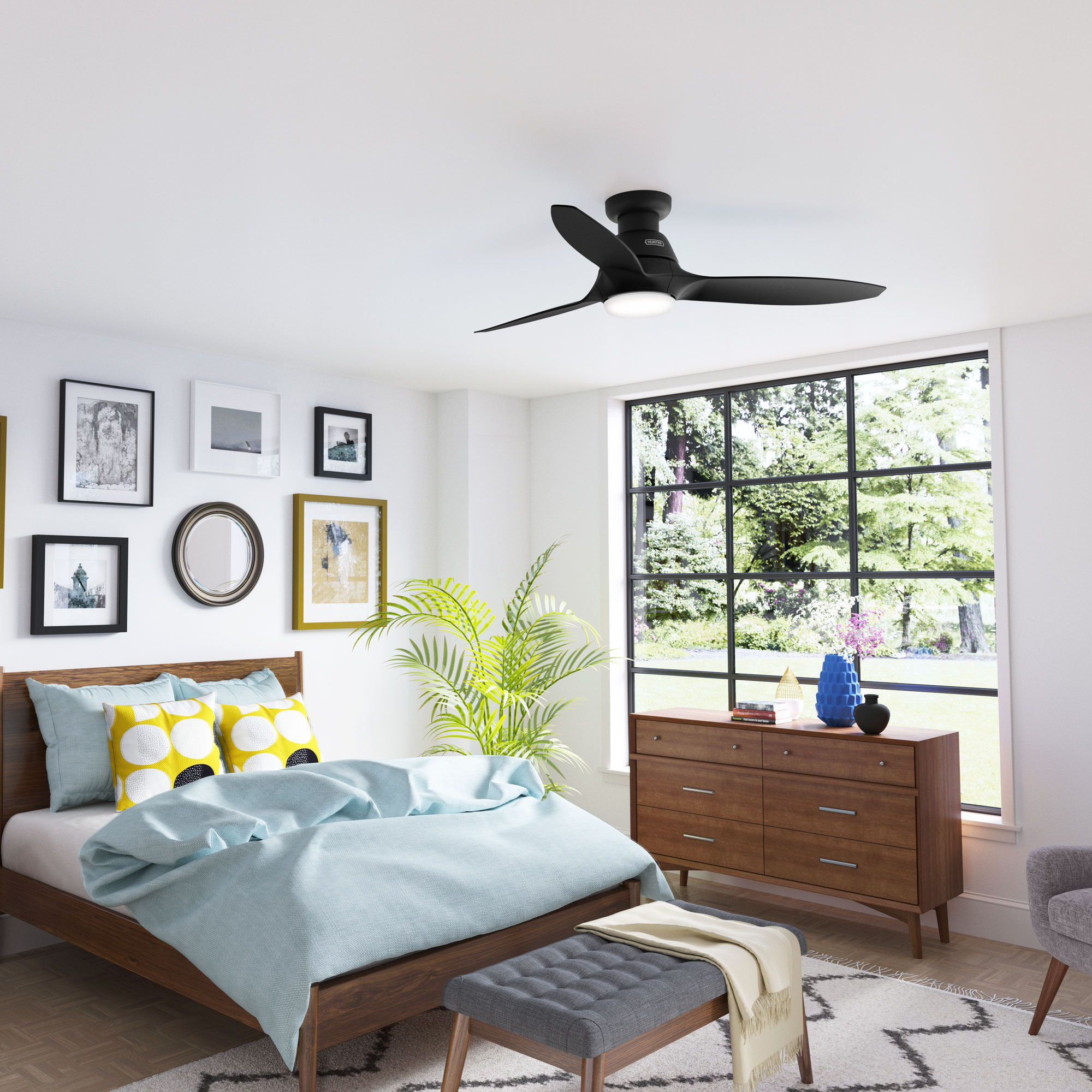 Ein Schlafzimmer mit einem schwarzen Deckenventilator, einem Bett mit blauer Bettwäsche und Kunst an der Wand.