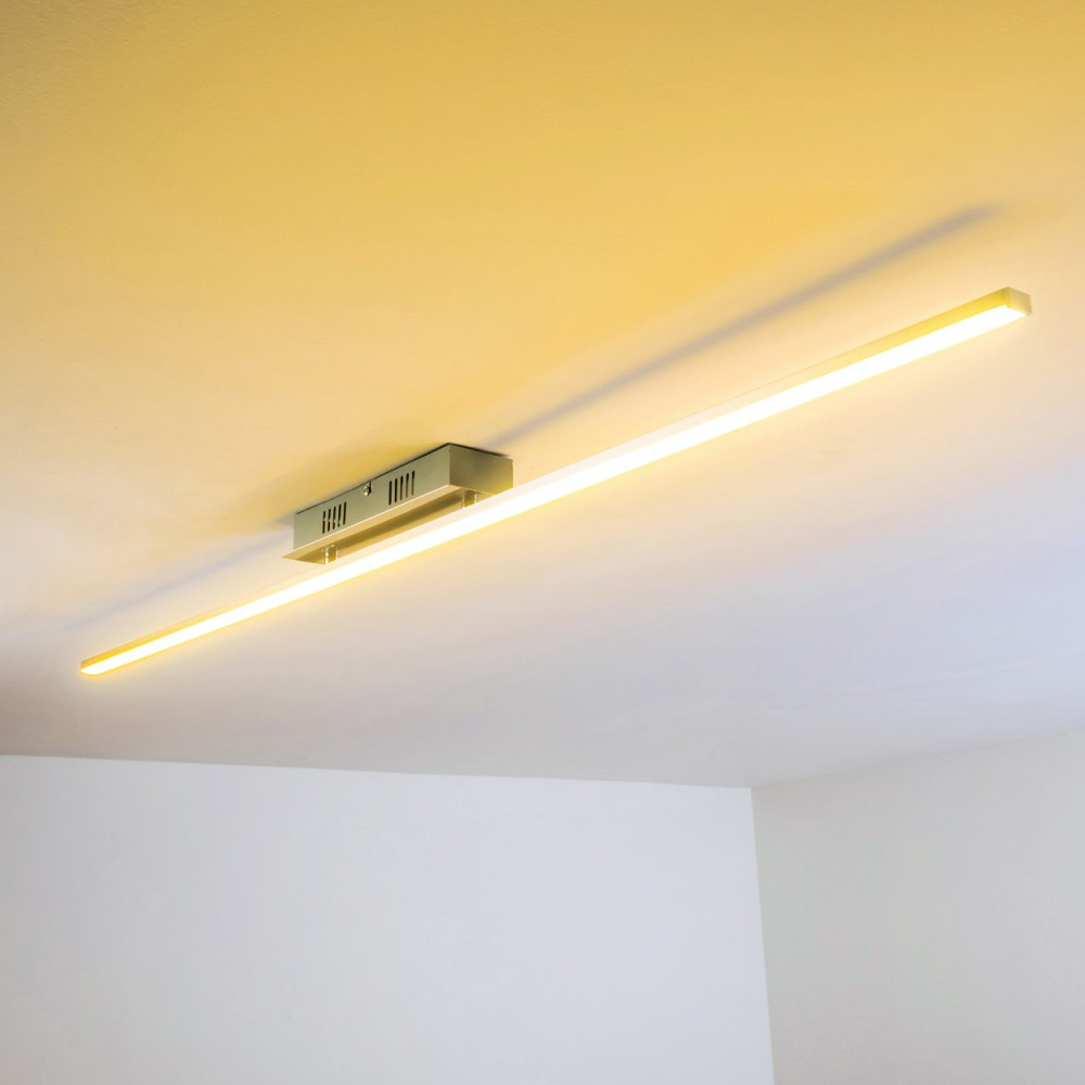 Eine Deckenleuchte mit einem langen, hellen Lichtbalken. Der Hintergrund ist eine weiße Decke.