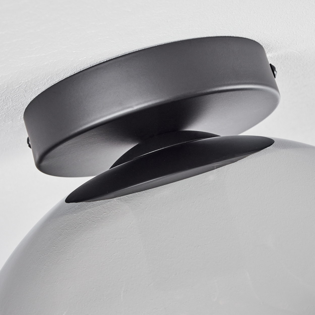 Nahaufnahme einer Deckenlampe, die den schwarzen Sockel und die Glaskugel zeigt.