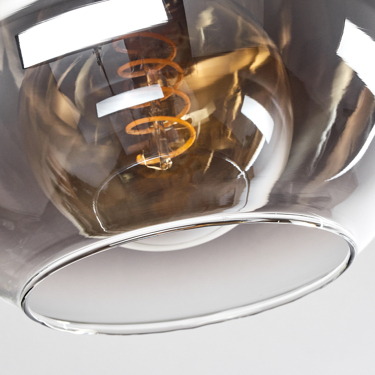 Nahaufnahme einer Glaslampe mit sichtbarer Glühbirne. Die Lampe hat einen weißen Rand und dunkles Glas.