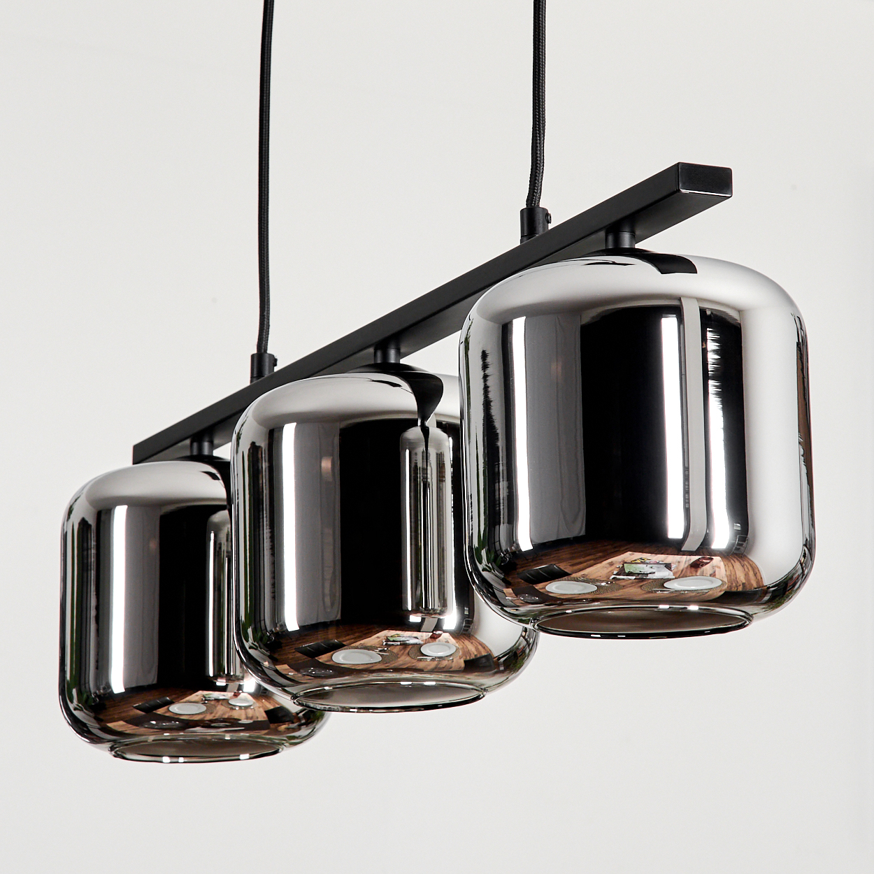 Drei Pendelleuchten mit glatter, reflektierender Oberfläche. Sie hängen vor einem weißen Hintergrund.