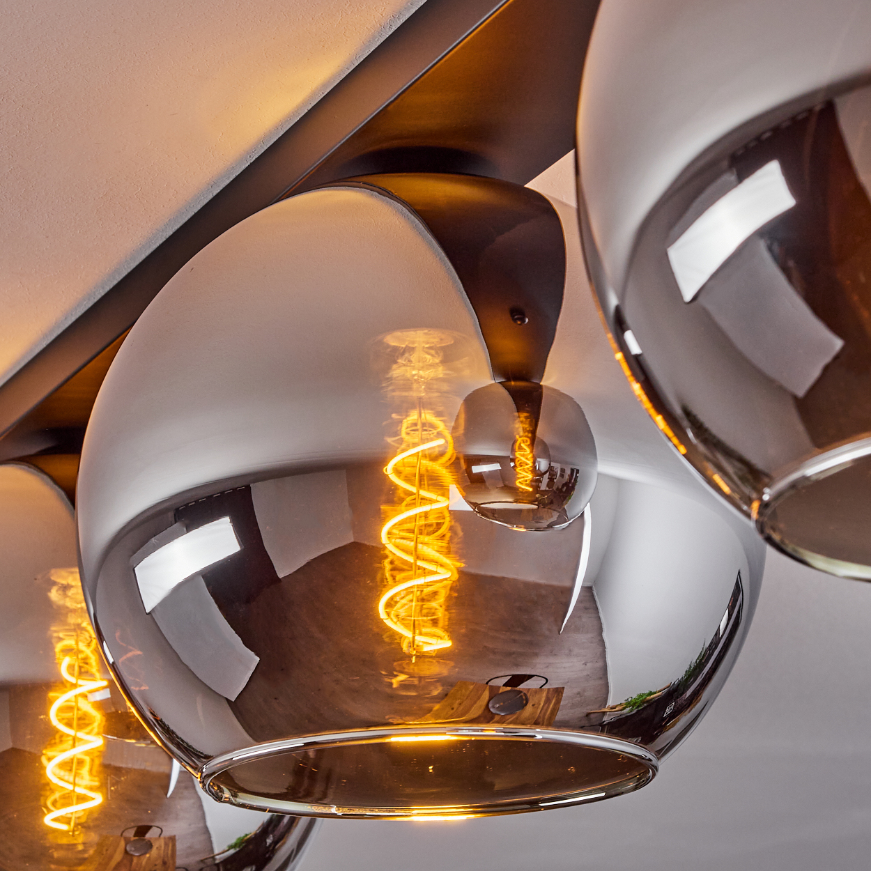 Nahaufnahme von beleuchteten Hängelampen. Die Glühfäden der Glühbirnen sind sichtbar. Die Lampen reflektieren das Licht.