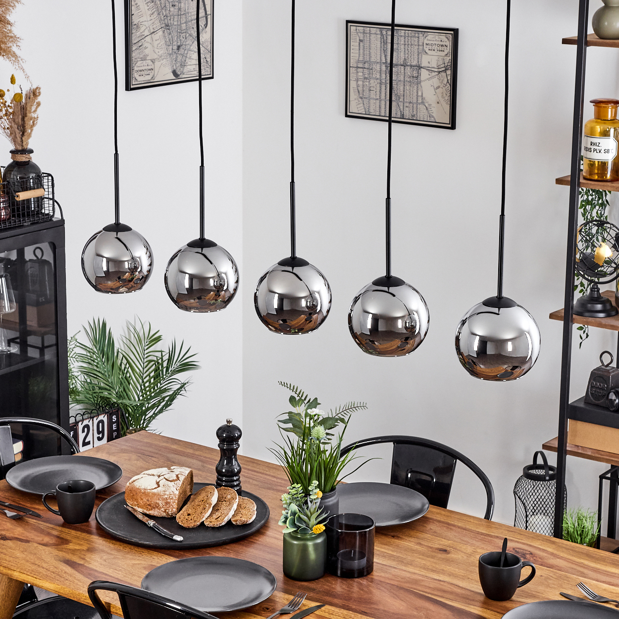 Esszimmer mit Tisch für eine Mahlzeit, mit Pendelleuchten über dem Tisch.